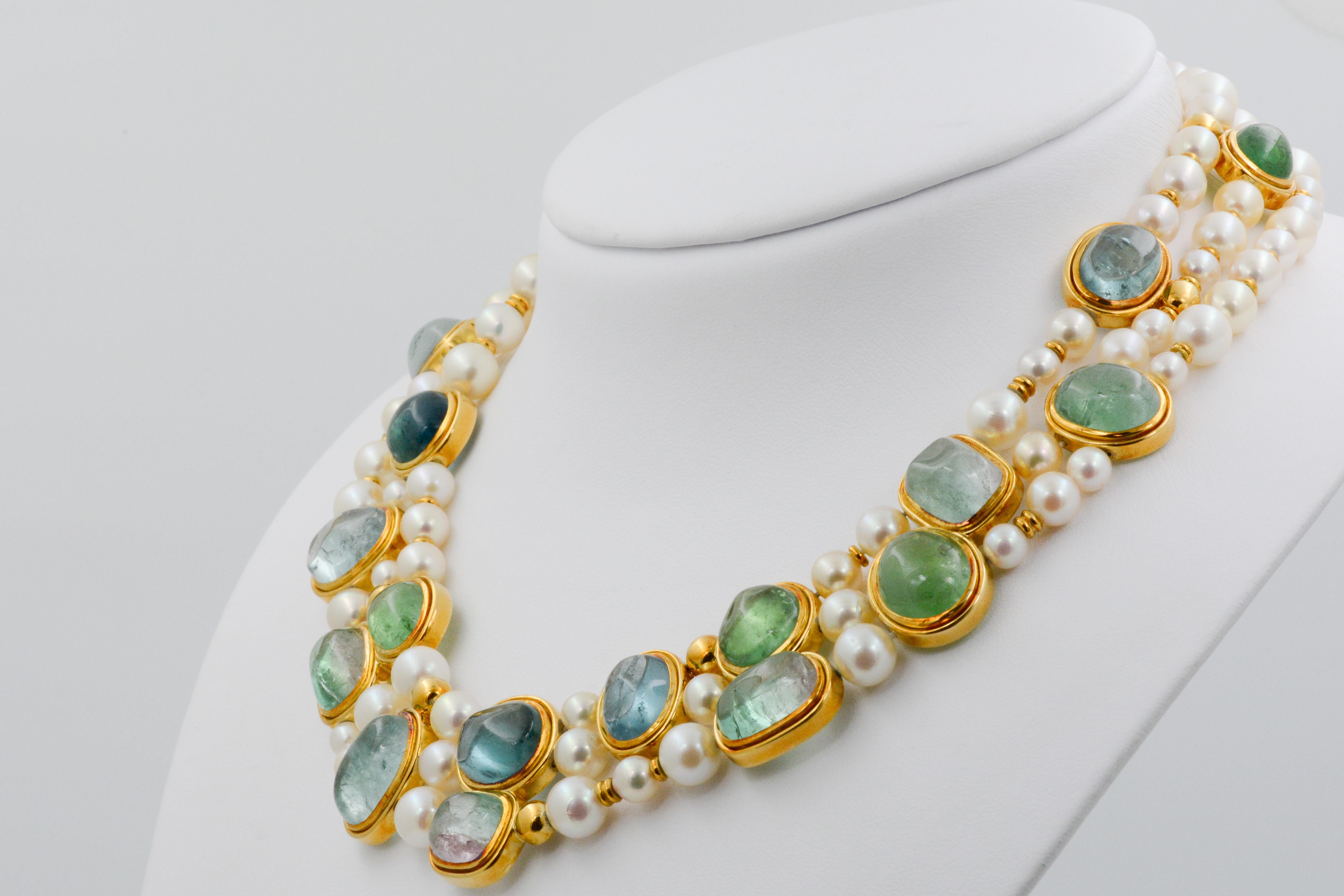 This decadent and vibrant triple strand pearl Leo De Vroomen necklace is a work of art with its specklings of 18k yellow gold, 10 tourmalines and 8 aquamarines. Each pearl measures at 5.25-8.25mm on the 18” long signed necklace. 