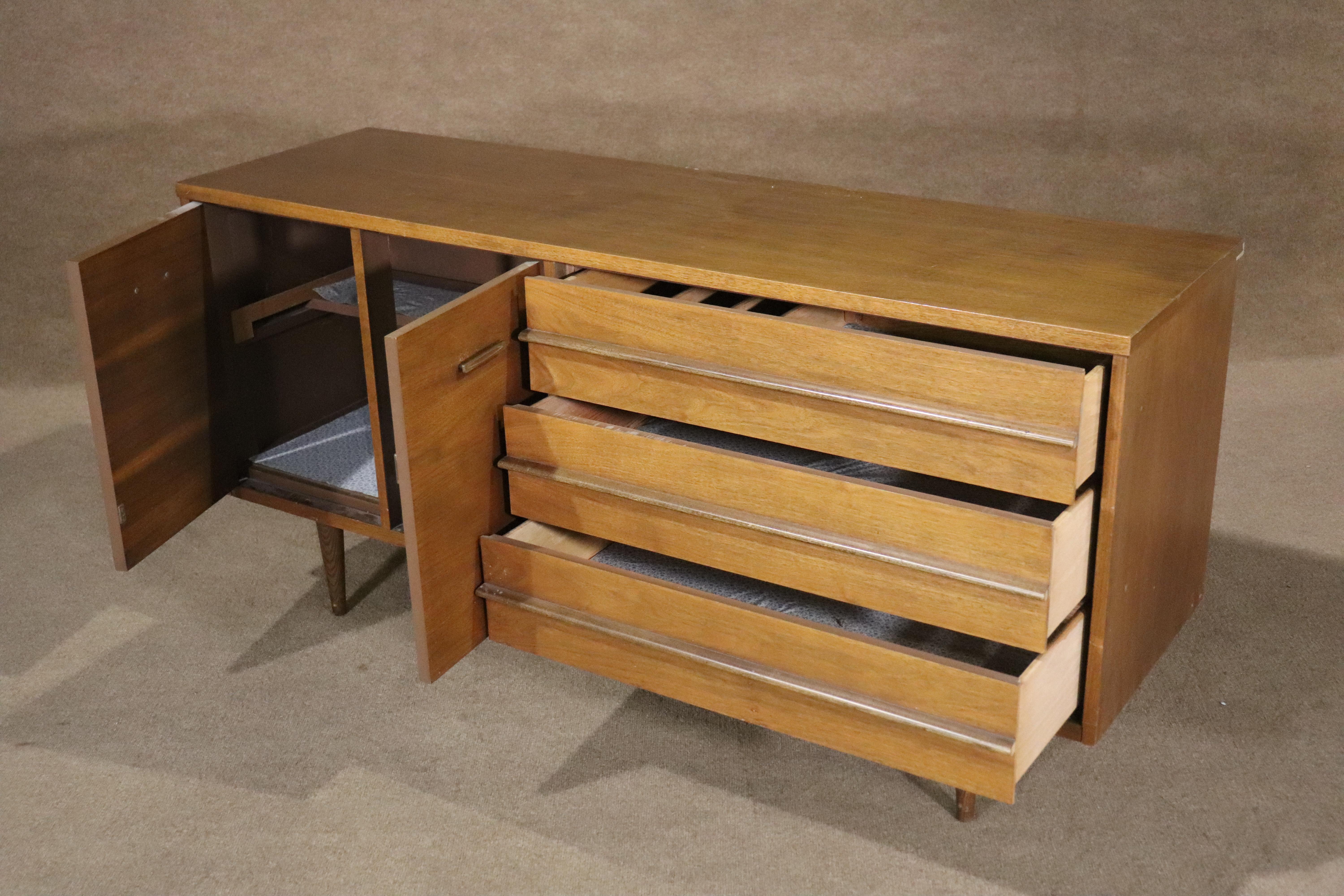 Low dresser with cabinet storage in walnut grain. Designed by Leo Jiranek for Bassett Furniture in the 1960s. Mid-century style that fits in your modern home.
Please confirm location NY or NJ
