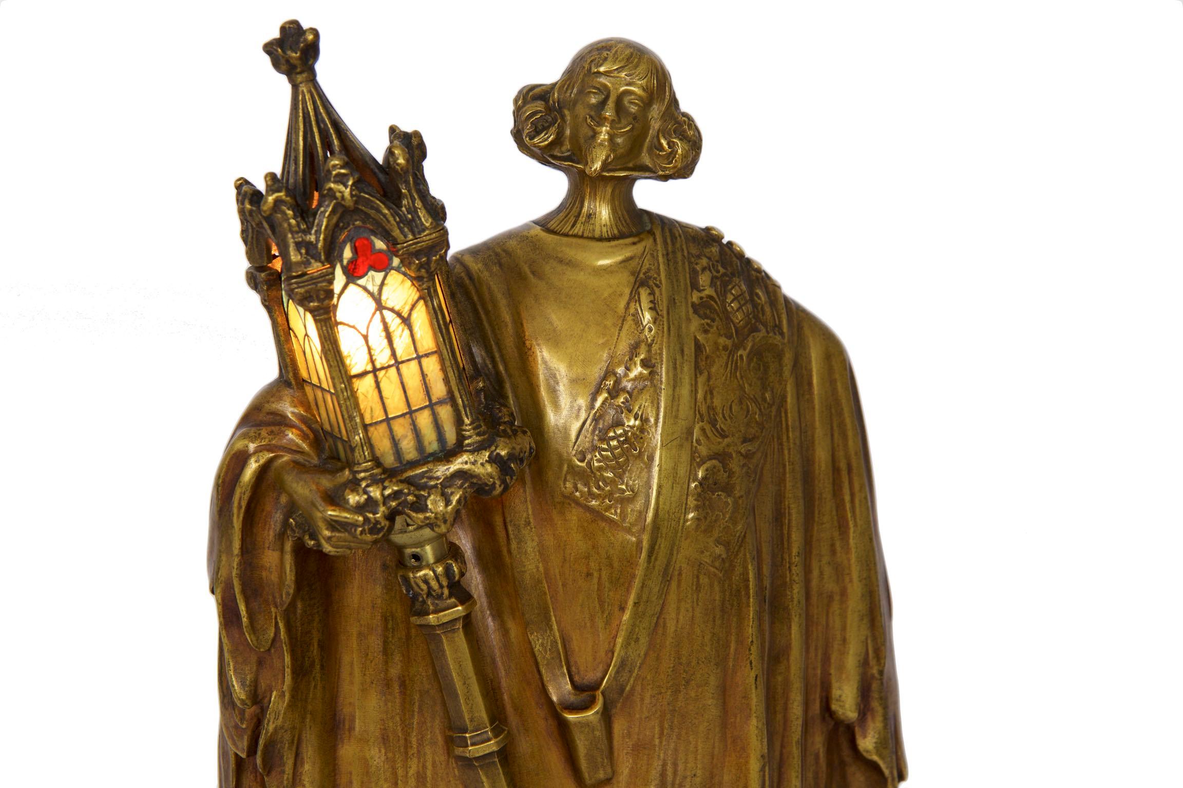 A very rare figural lamp by Léo Laporte-Blairsy, it depicts a mustached man in long robes carrying a Gothic lantern on post with his head held high. Tiny pieces of cut glass in iron astragals make up the three colored panels of the lantern, this