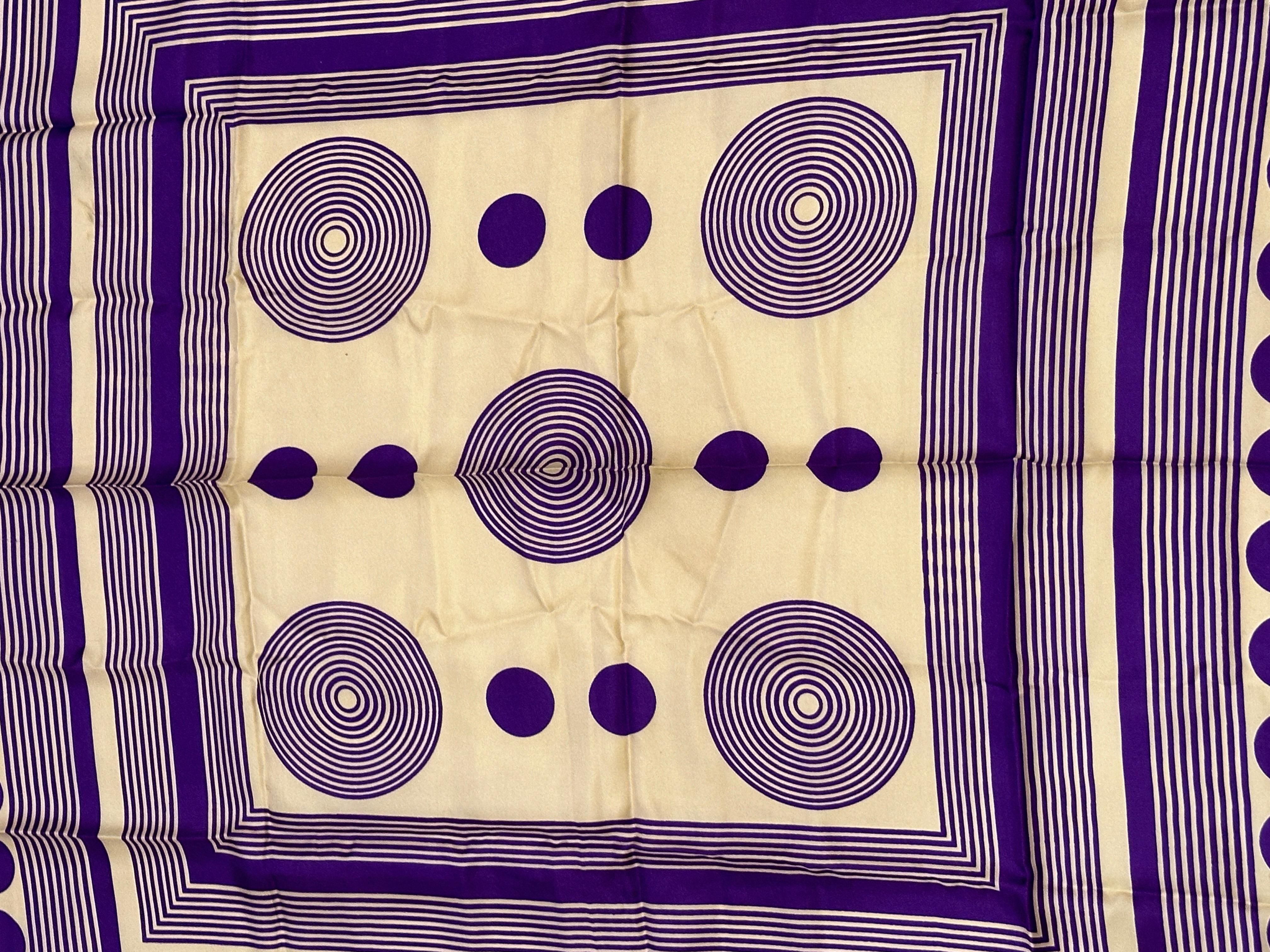 Leo Narducci associe des couleurs ivoire et un violet riche à un imprimé abstrait pour créer un foulard en soie audacieux et fantaisiste. L'écharpe est finie avec des bords roulés à la main et mesure 30 1/2 pouces par 30 pouces. Fabriquées en Italie.