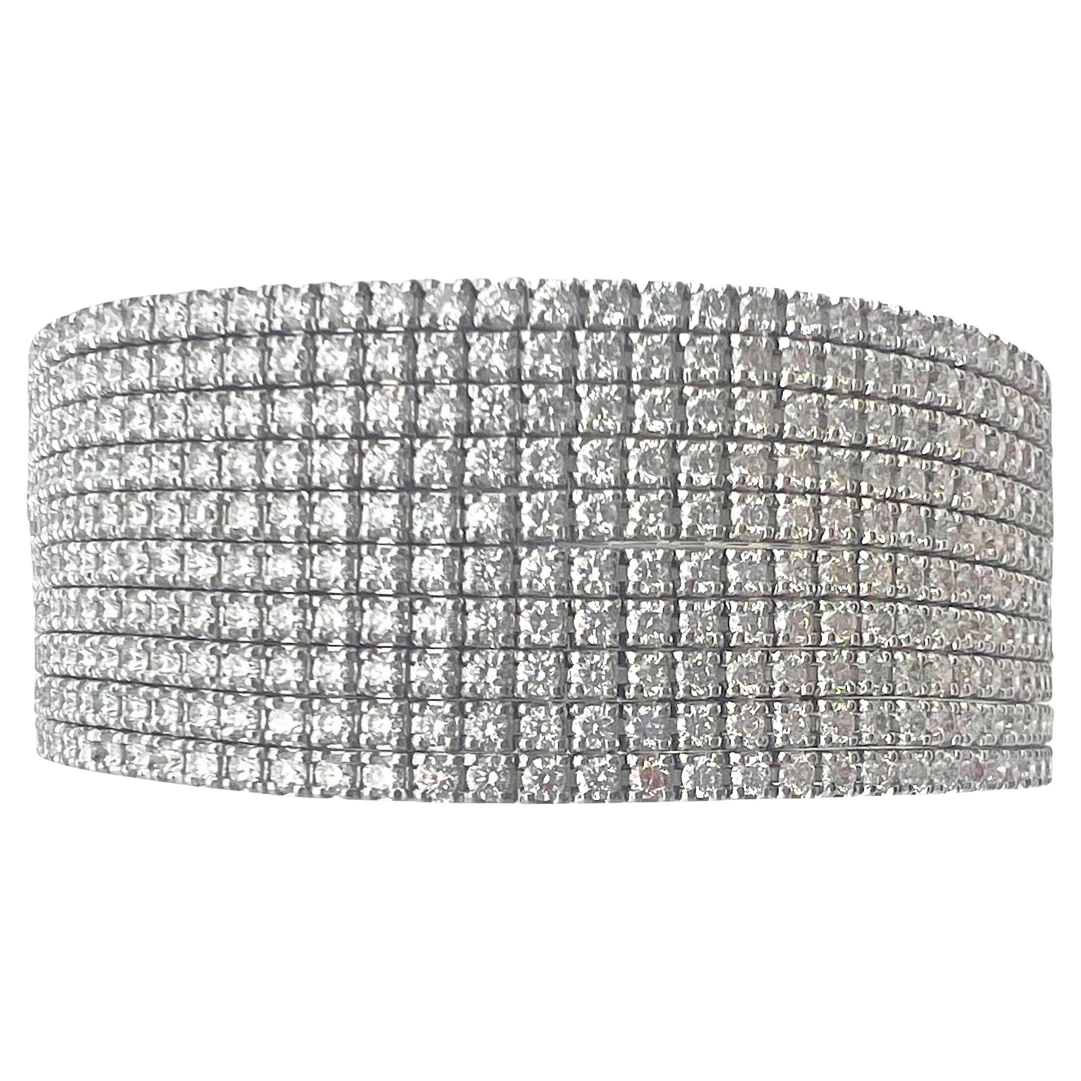 Multi-row diamond bracelet in 18k white gold, featuring ten diamond line bracelets joined together near the clasp. 890 round brilliant-cut diamonds weighing 16.23 total carats (F-G color, VVS-VS clarity). Clasp is a fold-over bar design which snaps