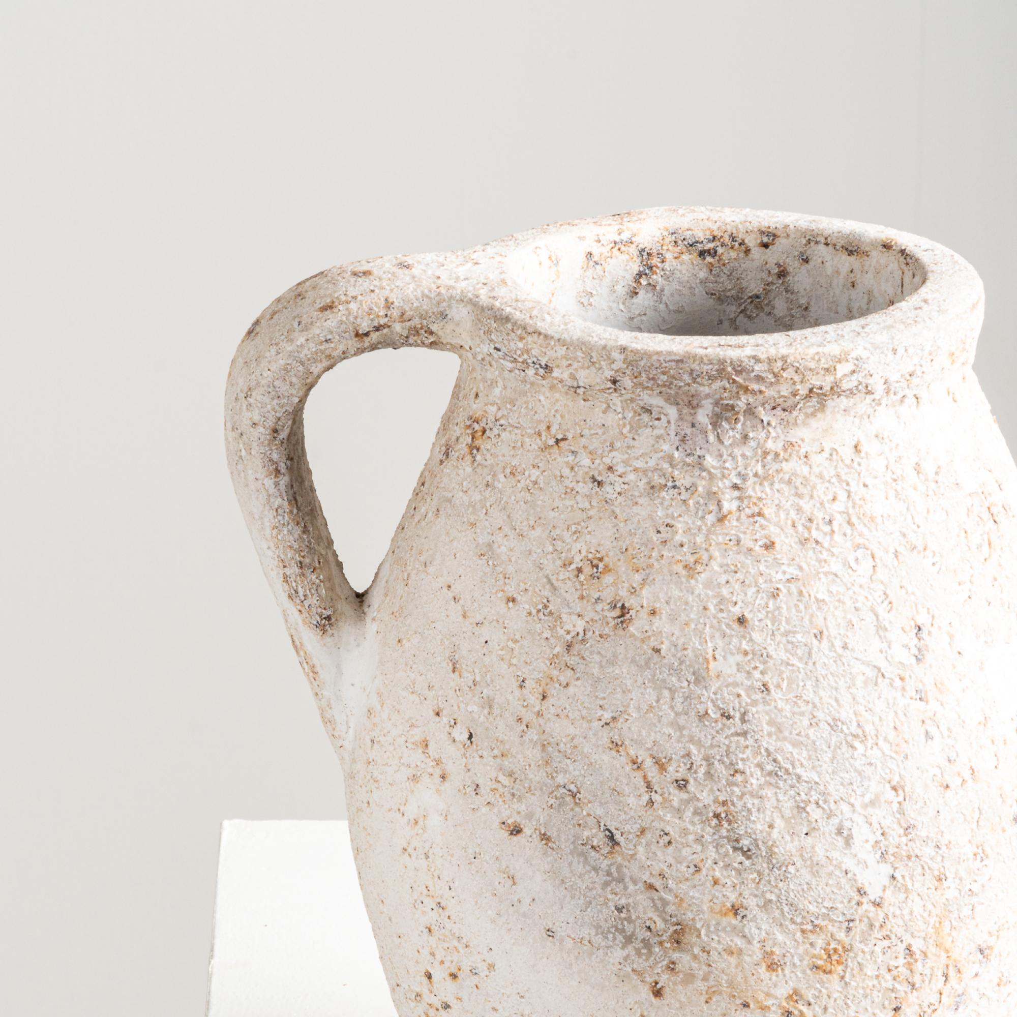 Il Vaso Leo, con la sua forma distintiva, valorizza sottilmente le vignette grazie ai dettagli strutturati. Realizzato a mano in terracotta e rifinito in bianco invecchiato, emana un fascino rustico che aggiunge un tocco di eleganza alla sua