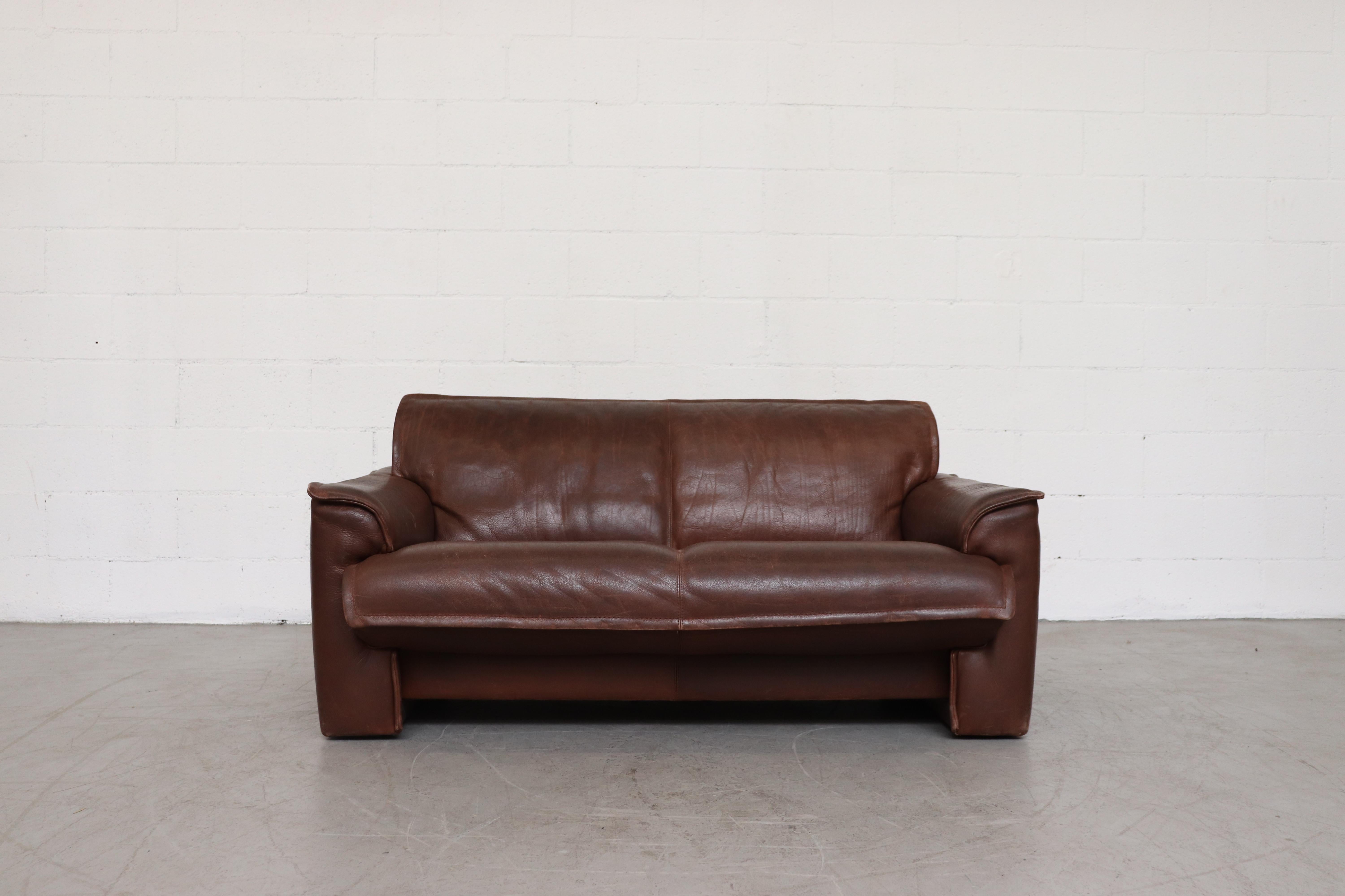 Leolux buffalo leather love seat with heavy patina. In original condition with visible signs of wear. Wear is consistent with its age and usage. A similar slightly lighter love seat is available, listed separately. In original condition with some