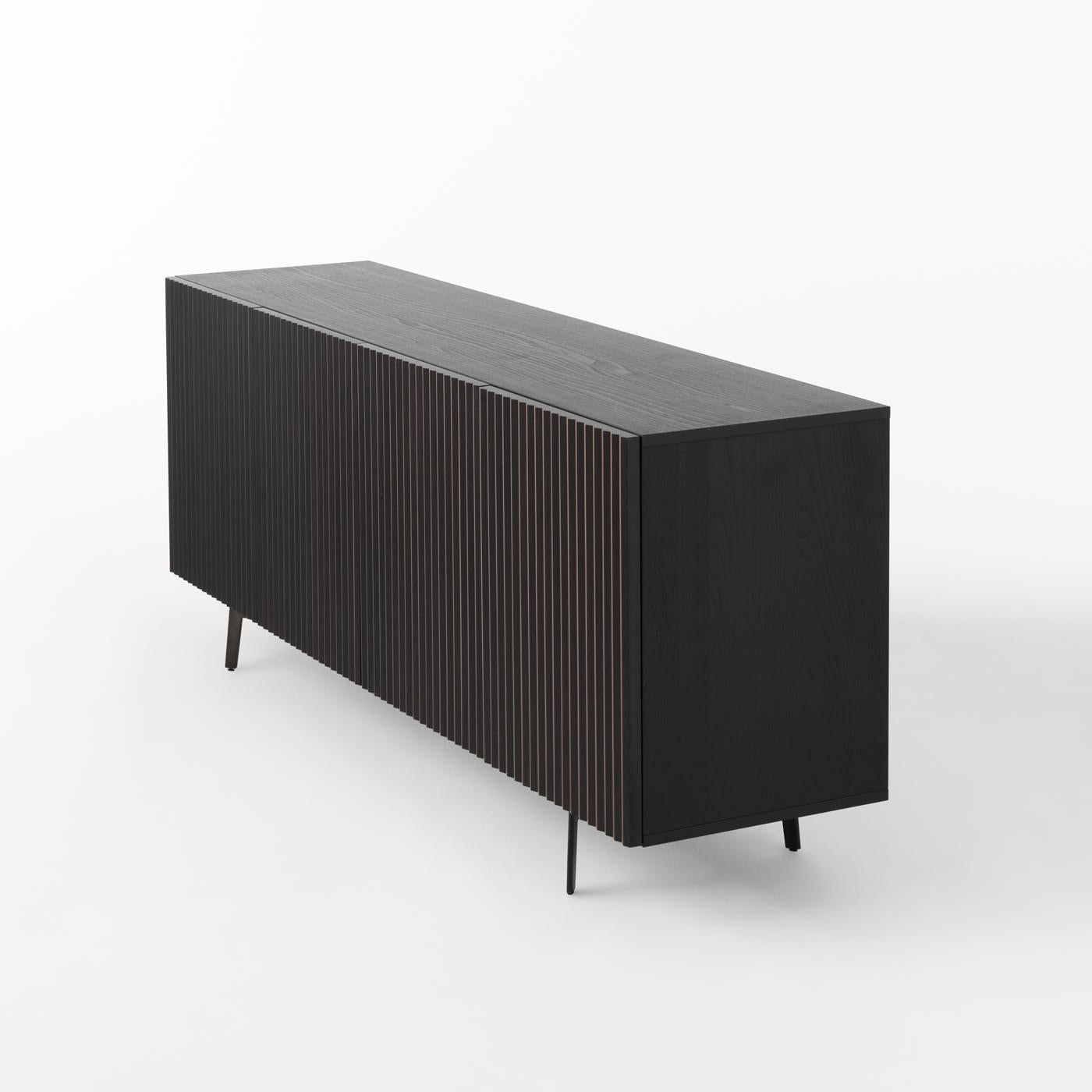 An interplay of captivating optical effects that change based on the standpoint, this sideboard designed by StH has a glossy black-lacquered wooden frame raised on four angled black powder-coated iron legs. Looking at it from the front, the four