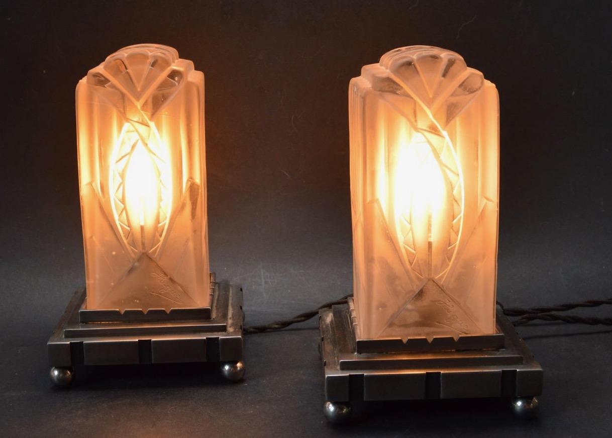 A wonderful French 1930s pair of art deco table lamps by the Paris-based company of Léon Hugue, A nickel-plated solid brass or bronze base holds a signed cube in a clear frosted molded-pressed glass. This rare and outstanding lamp design has been