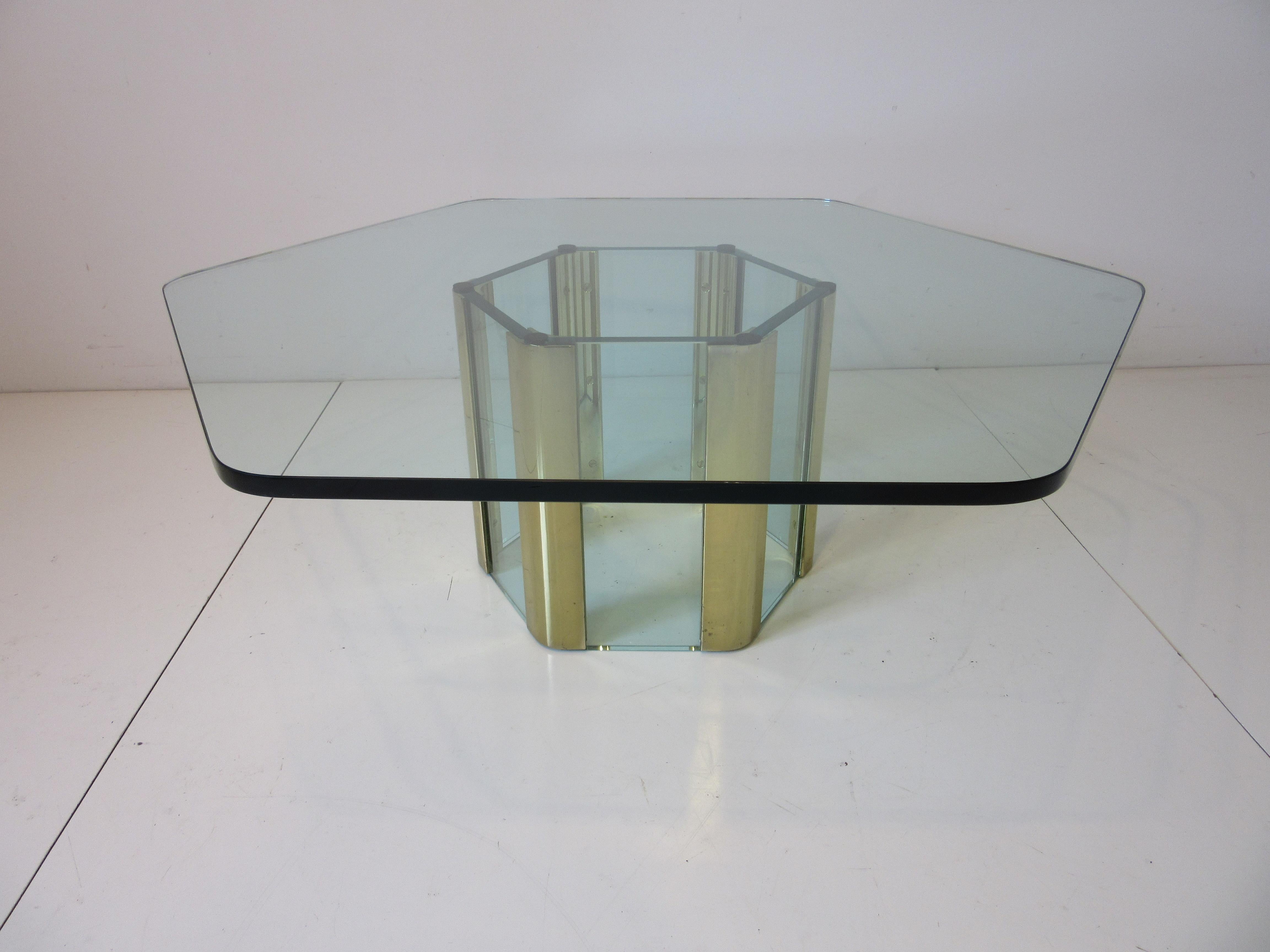 A very well crafted quality thick plate glass coffee table with hexagon cut top and matching base with heavy brass inserted panels holding panels of glass. A rich but light look from the 1970's, manufactured by the Pace Furniture company for their