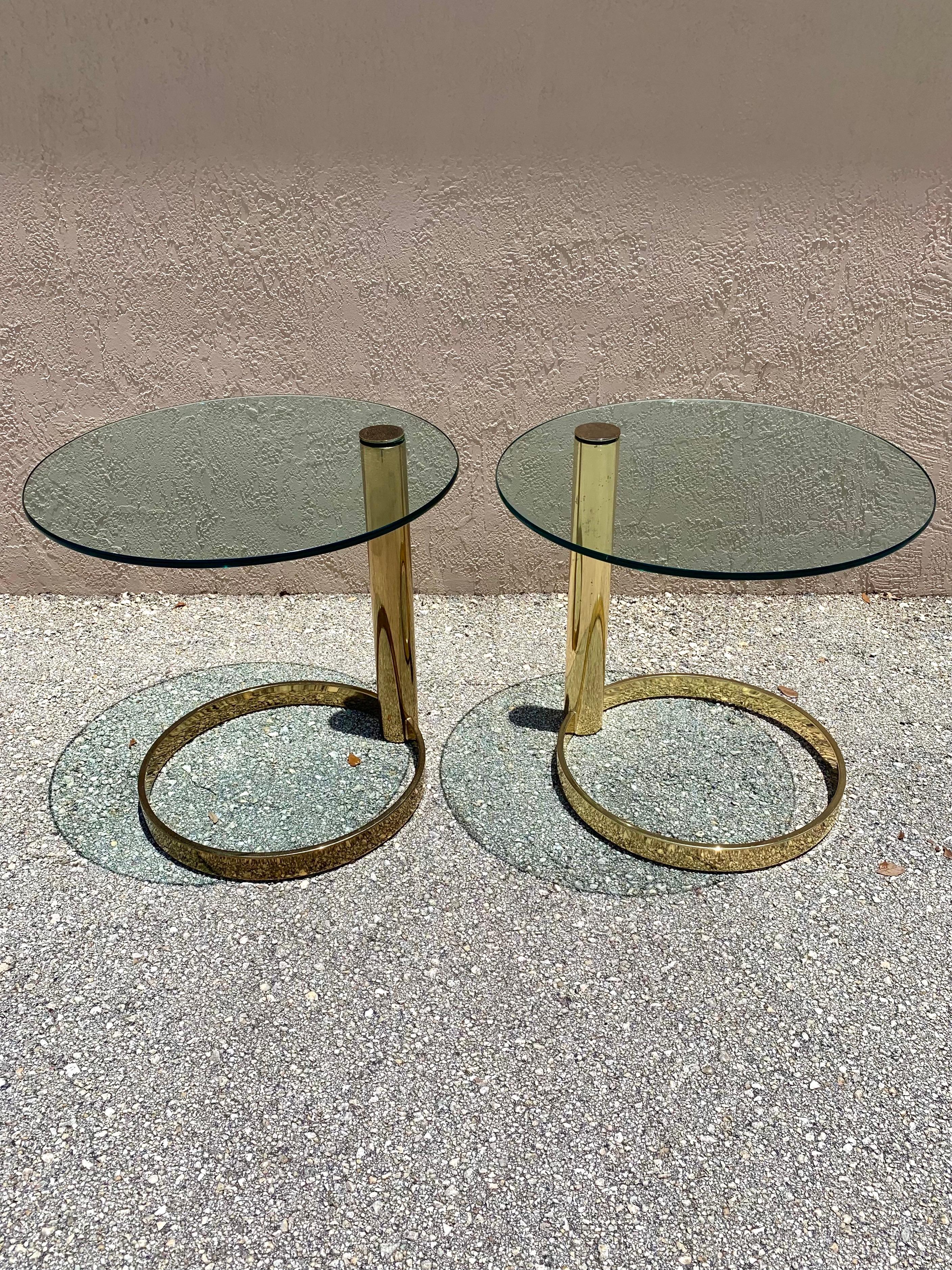 Pair of end tables designed by Leon Rosen for Pace. Brass cantilevered base with a thick glass table top. Exemplary design bridging the gap between Mid-Century Modern and Postmodern. 

Tempered glass attached to a singular brass cylinder which
