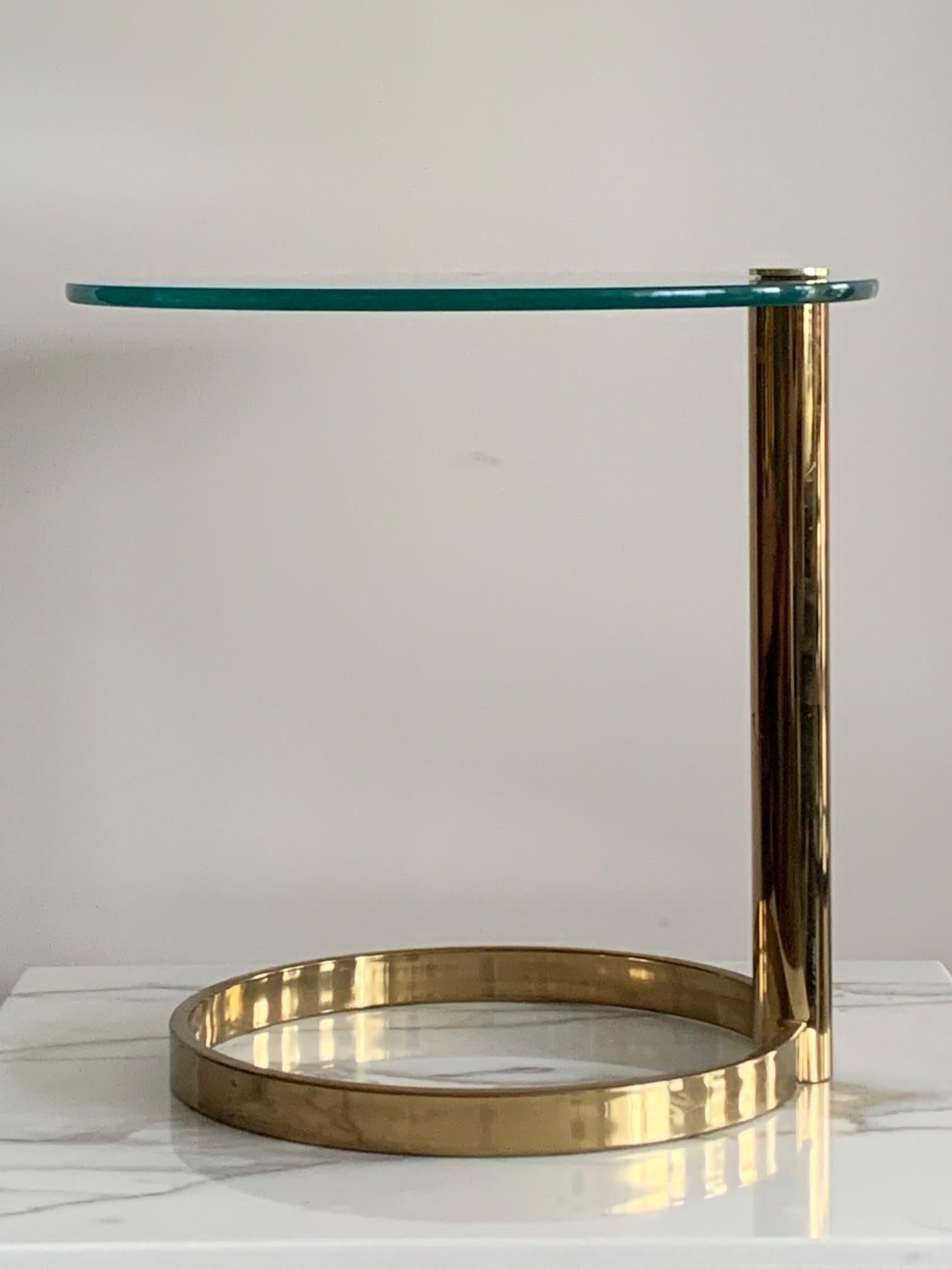 An unusual Mid-Century Modern Hollywood Regency brass and side table designed by Leon Rosen for the Pace Collection. The table features a circular brass base with a single brass pedestal and a thick cantilevered glass top. Perfect as an occasional