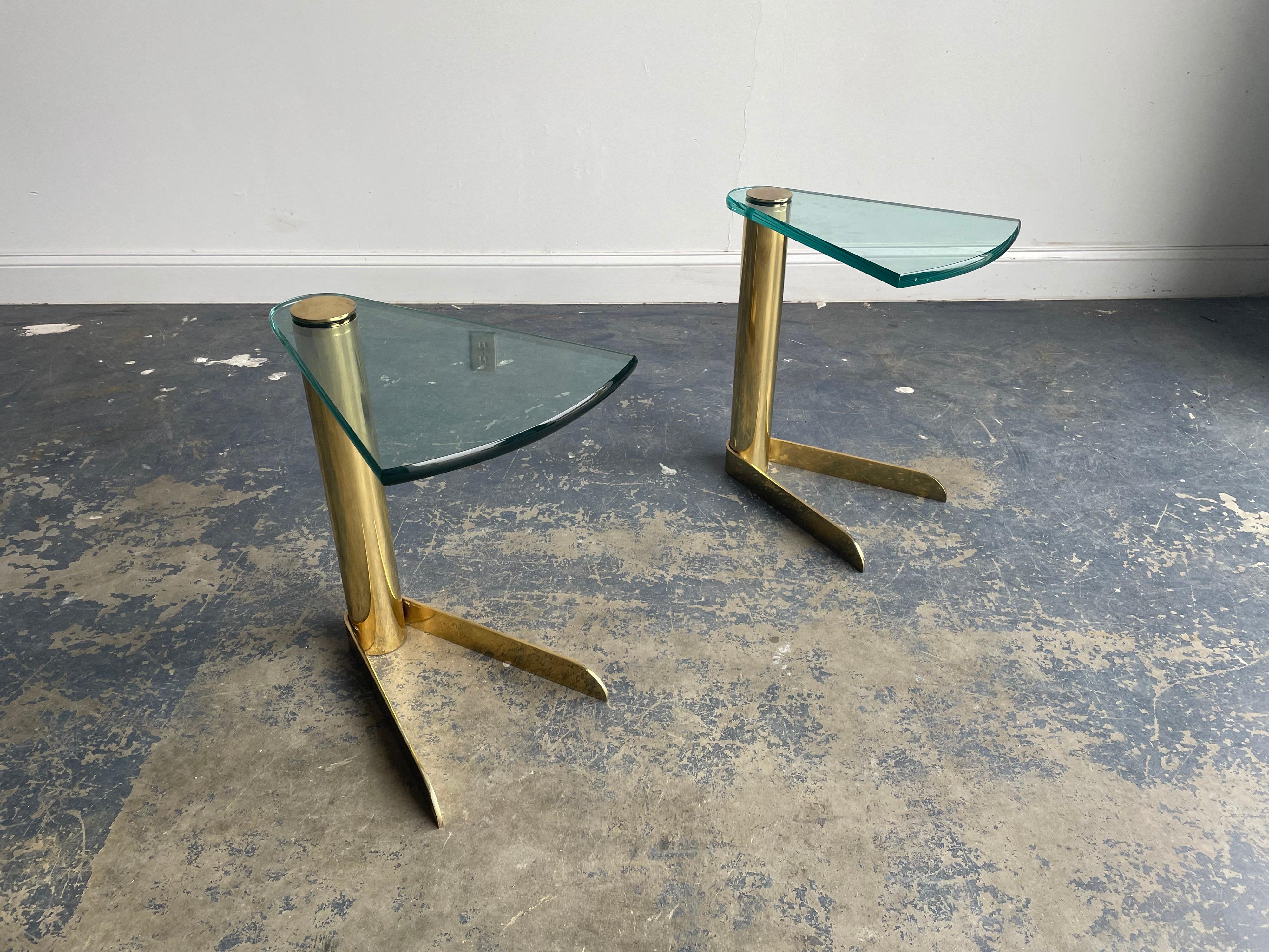 Pair of cantilevered drink or side tables by Pace Collection. Thick rotating wedge shaped glass supported by brass plated metal. 

Measures: 18” deep
13.5” wide
20.25” tall.