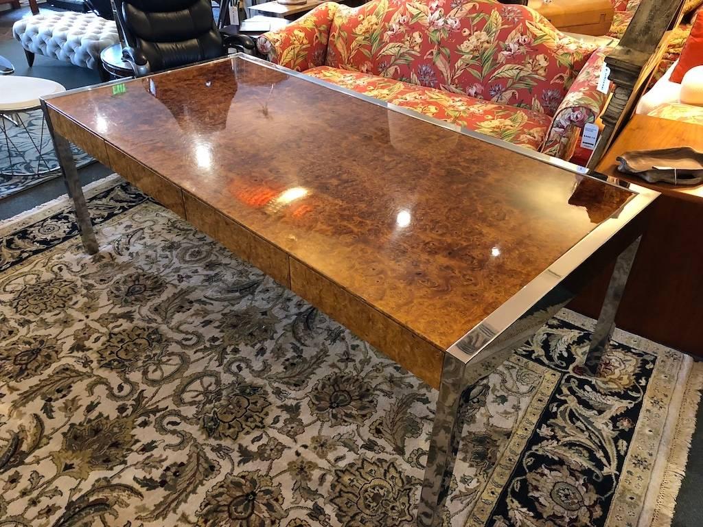 An exquisite executive desk by Leon Rosen for Pace collection. Crisply framed in polished stainless steel, the vintage desk oozes success in rich olive wood burl. A few spots of uneven coloring. Three drawers and two pull out shelves.




      