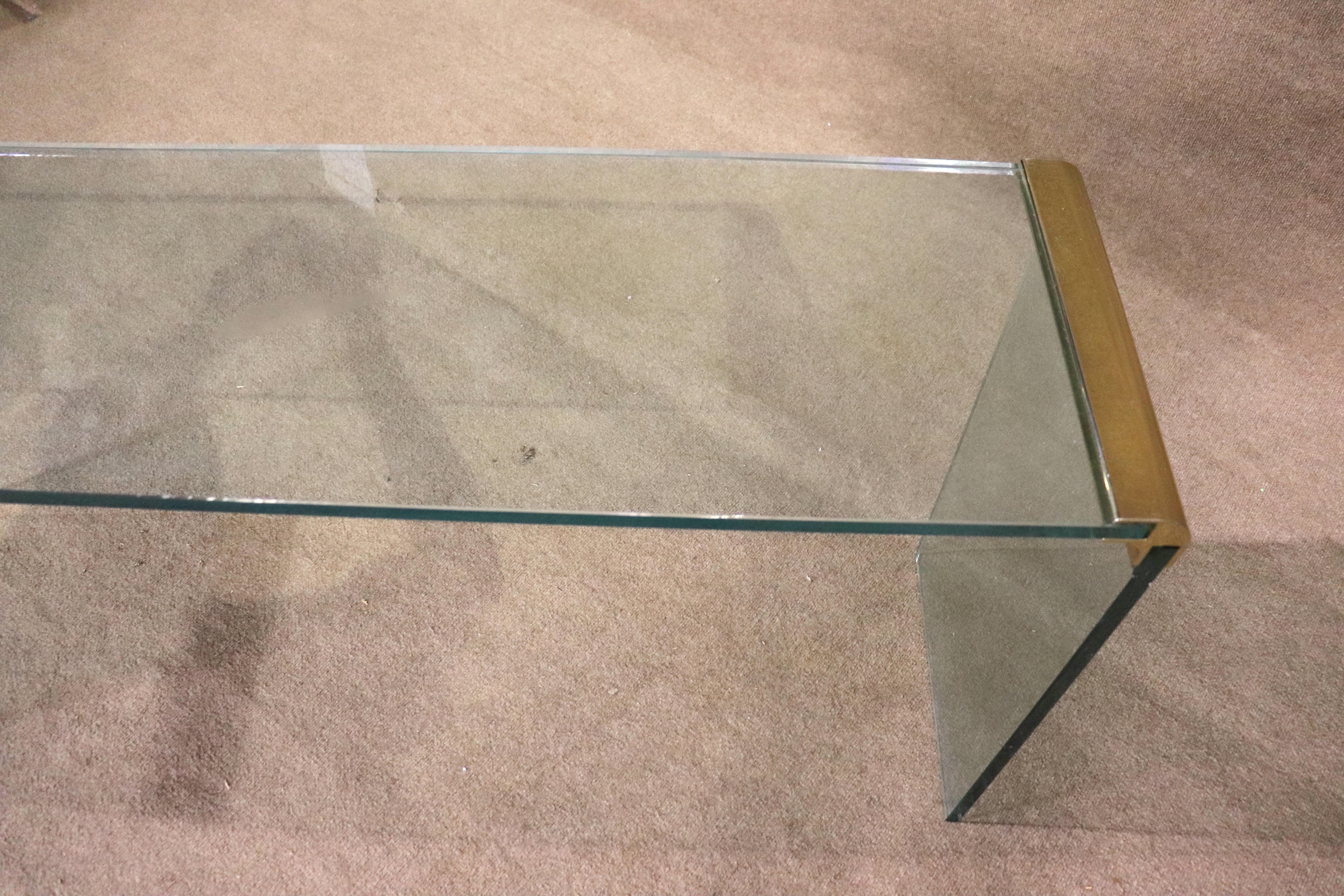 Clear glass console table by Pace, and designed by Leon Rosen. A simple modern design of three glass panes connected by rounded waterfall edges in brass.
Please confirm location NY or NJ