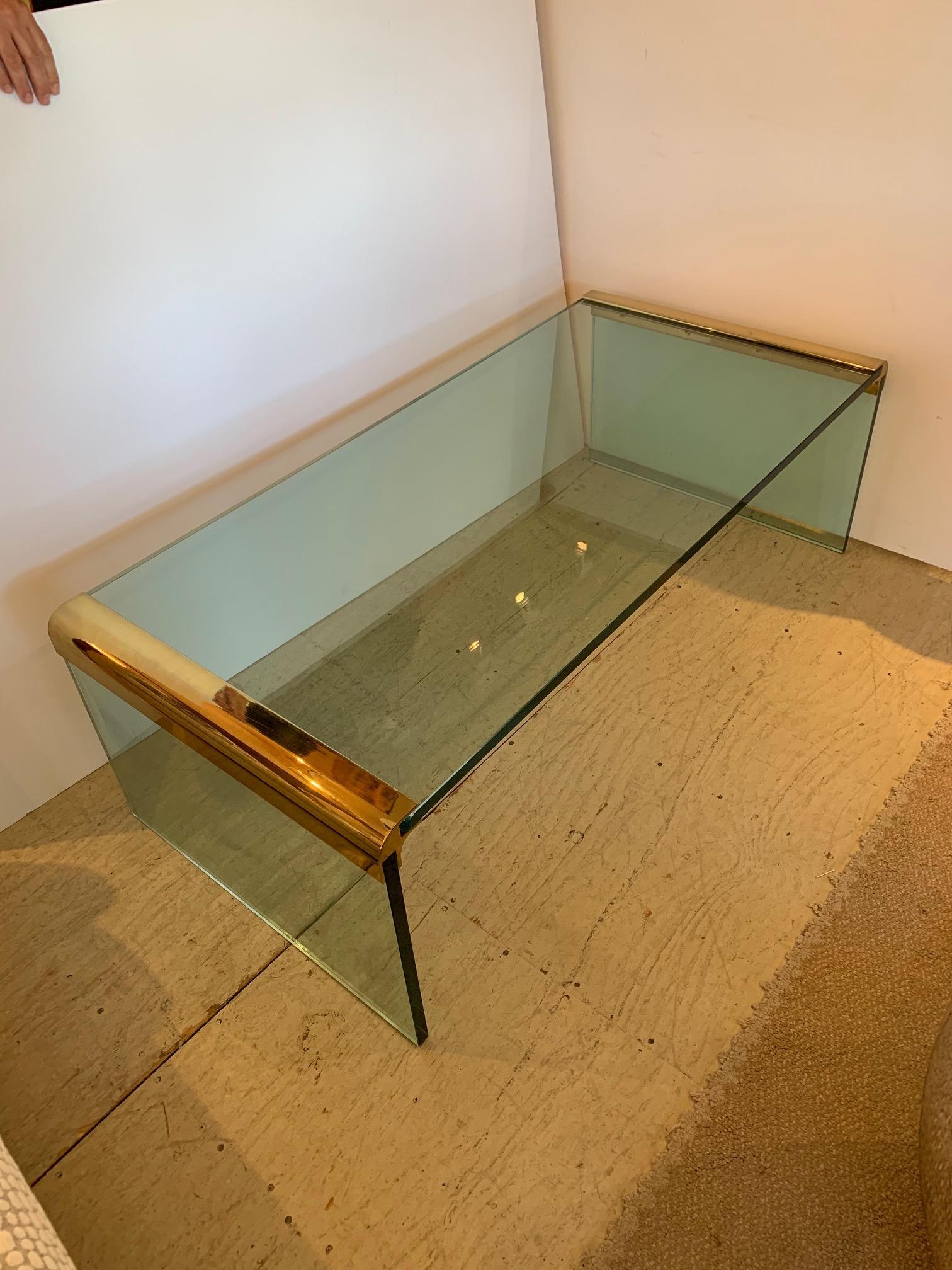Thick plate glass top and sides joined by heavy brass waterfall corners. Super sleek and iconic midcentury design.