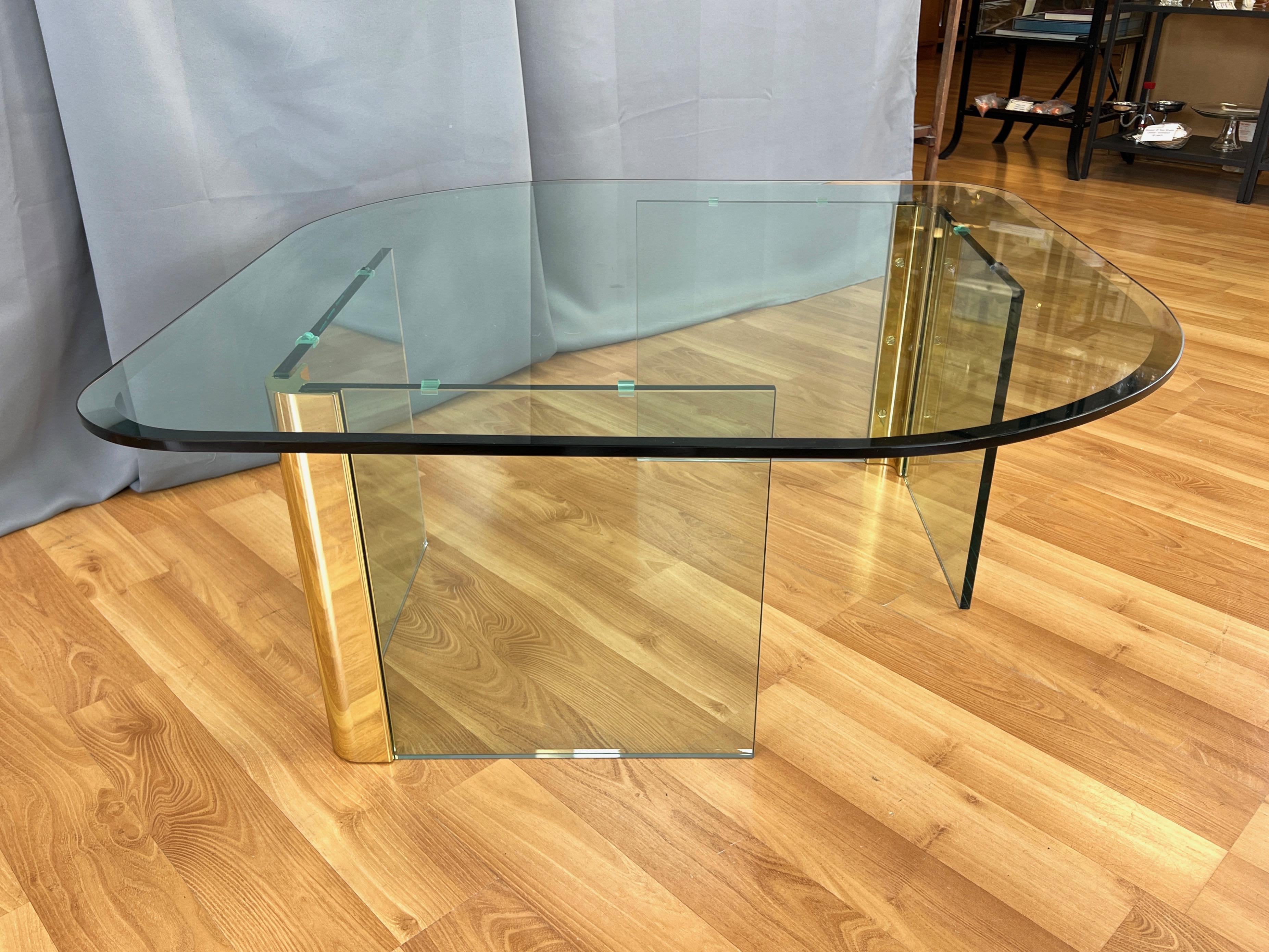 A 1970s glass-top coffee table with brass and glass base by Leon Rosen for The Pace Collection.

Sleek minimalist design with a modernized Hollywood Regency vibe. Base comprised of two free-standing V-shaped elements, each with a gleaming brass