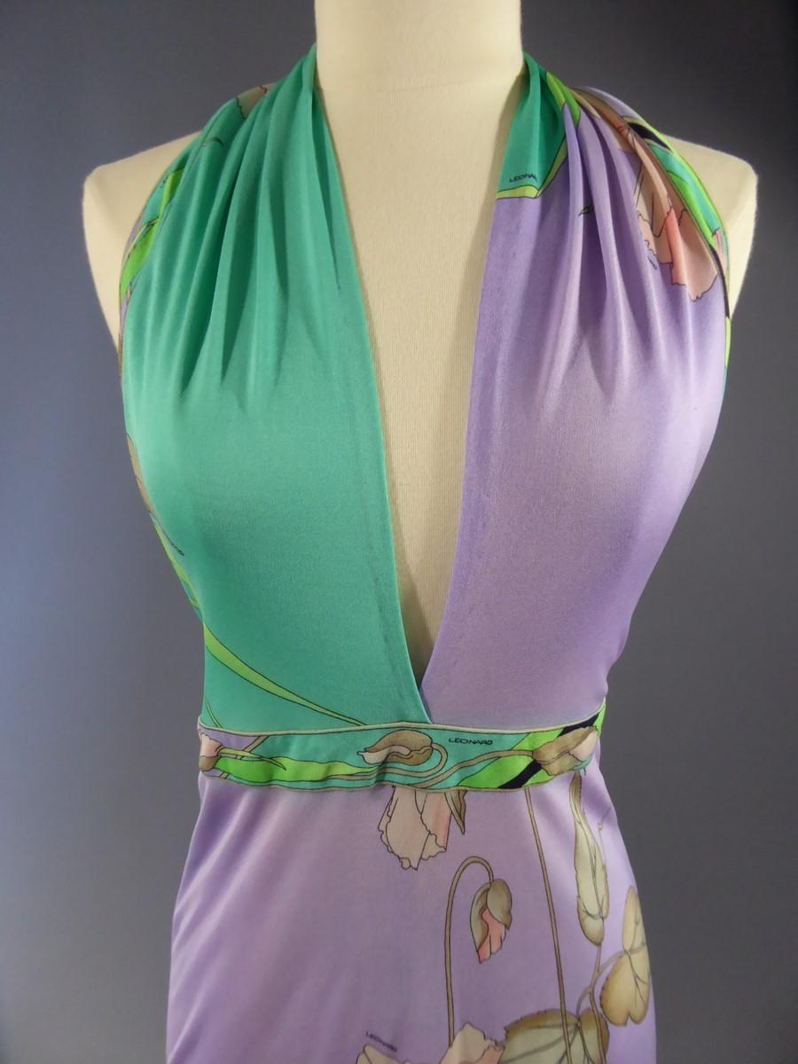 Circa 1990/2000
France

Long backless dress with poppy motifs, large leaves and rushes. Leonard label and signature in silk jersey print. Floral motifs in shades of green, purple, black and powdery pink. Ties in a scarf around the neck. Zip on the