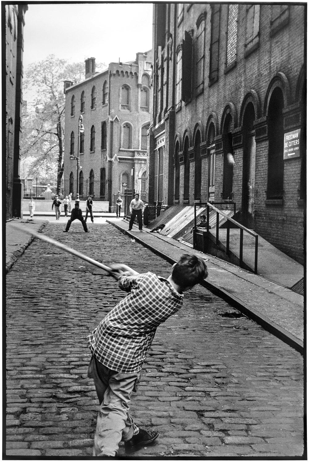 Stickball von Leonard Freed fängt Kinder ein, die in den Straßen von Little Italy im New York der 1950er Jahre das typisch amerikanische Baseballspiel spielen. Der amerikanische Fotograf Freed liebte das dokumentarische Erzählen und galt als