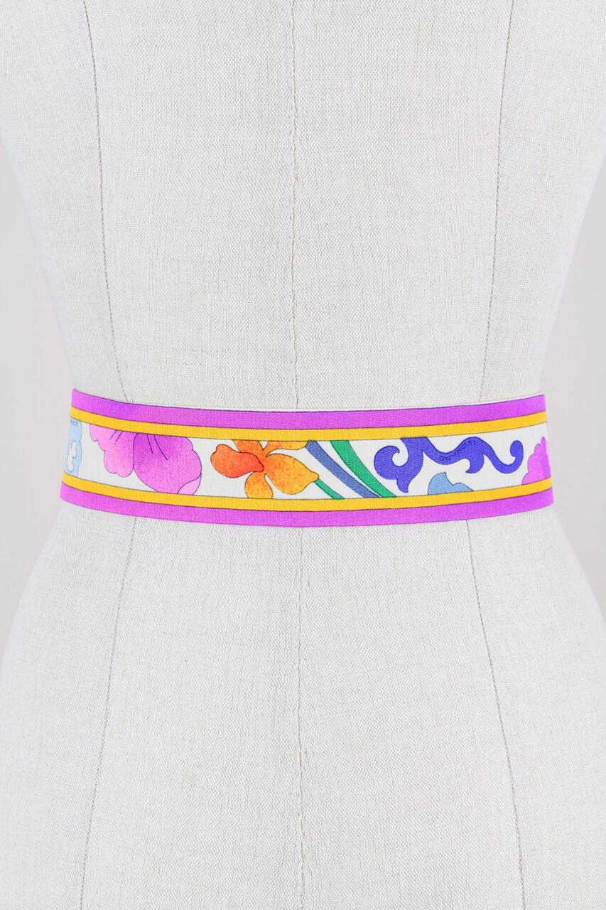 This striking Léonard Paris 1980s waist belt is made of silk covered off-white leather and features a vibrant signature Léonard floral print in lilac, yellow, blue and green against an off-white background. It fastens at the front with an elegant