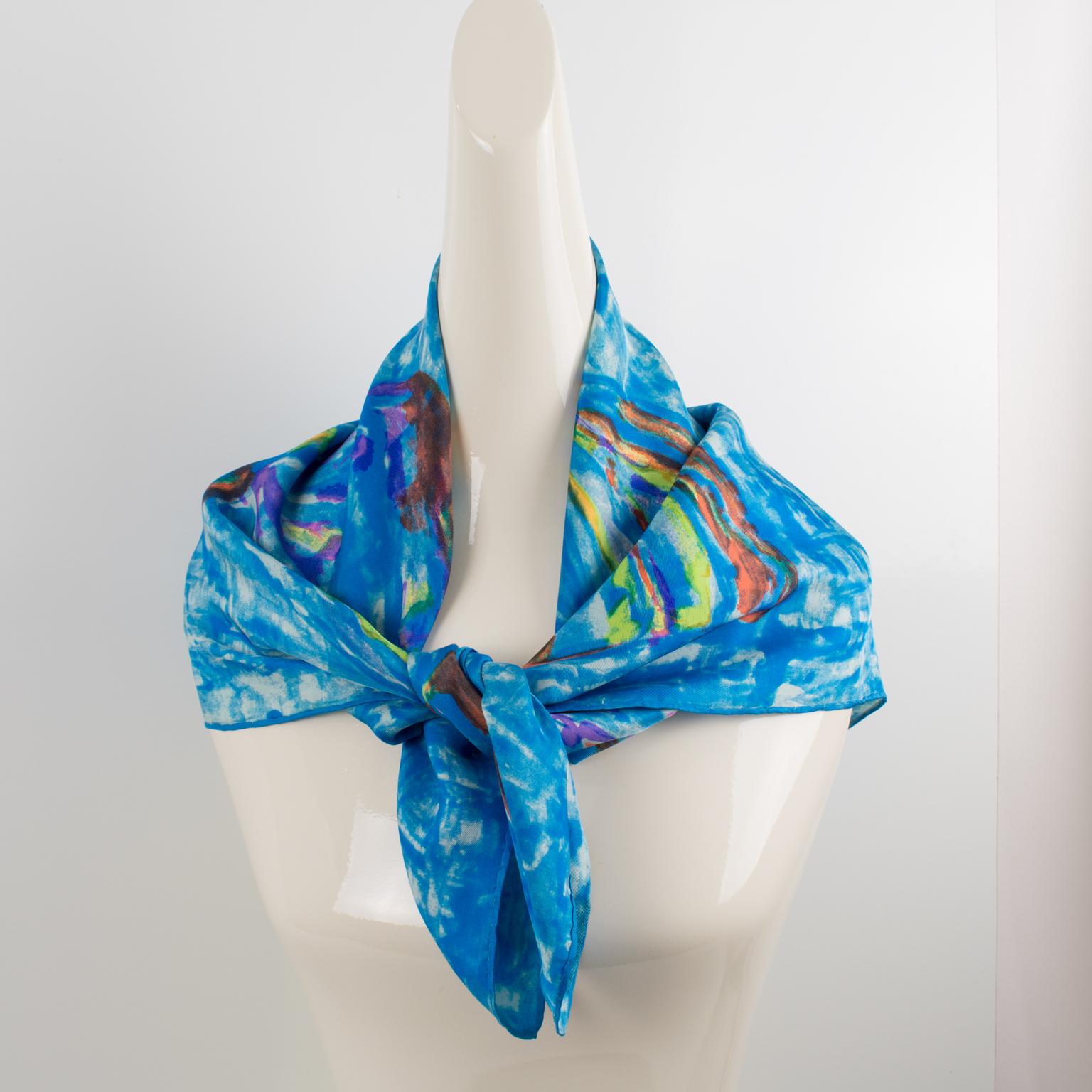 This beautiful silk scarf by Leonard Paris in blue and multicolor colors features a stylized butterfly design print. The brand signature is on the care tag. The combination of colors is bright and vibrant, with cerulean blue, orange, purple,