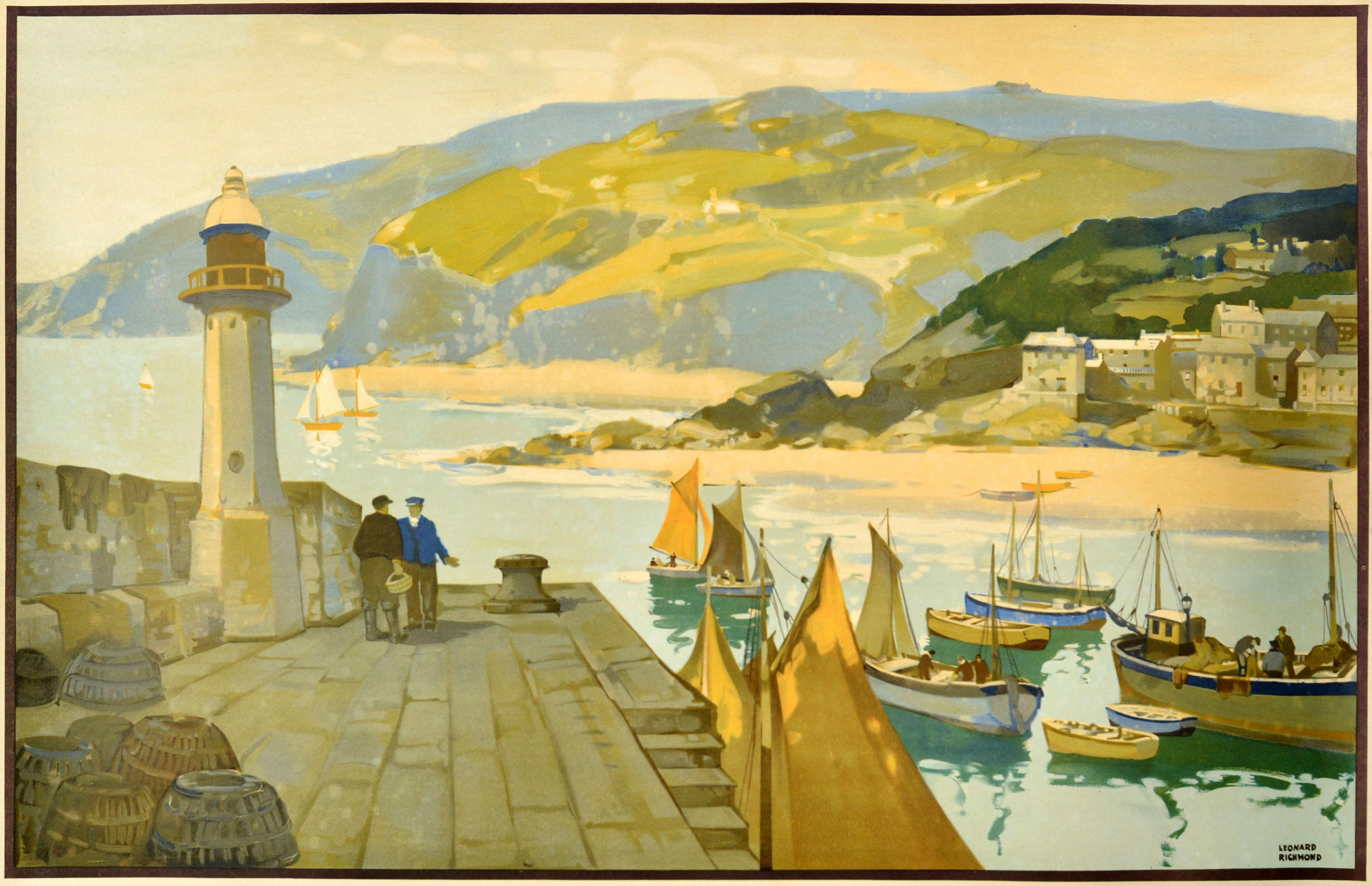 Original vintage GWR Great Western Railway poster for Cornwall featuring a scenic view of fishing boats in a Cornish harbour and men on the pier by a lighthouse with fishing nets in the foreground, a village above a sandy beach on the other side and