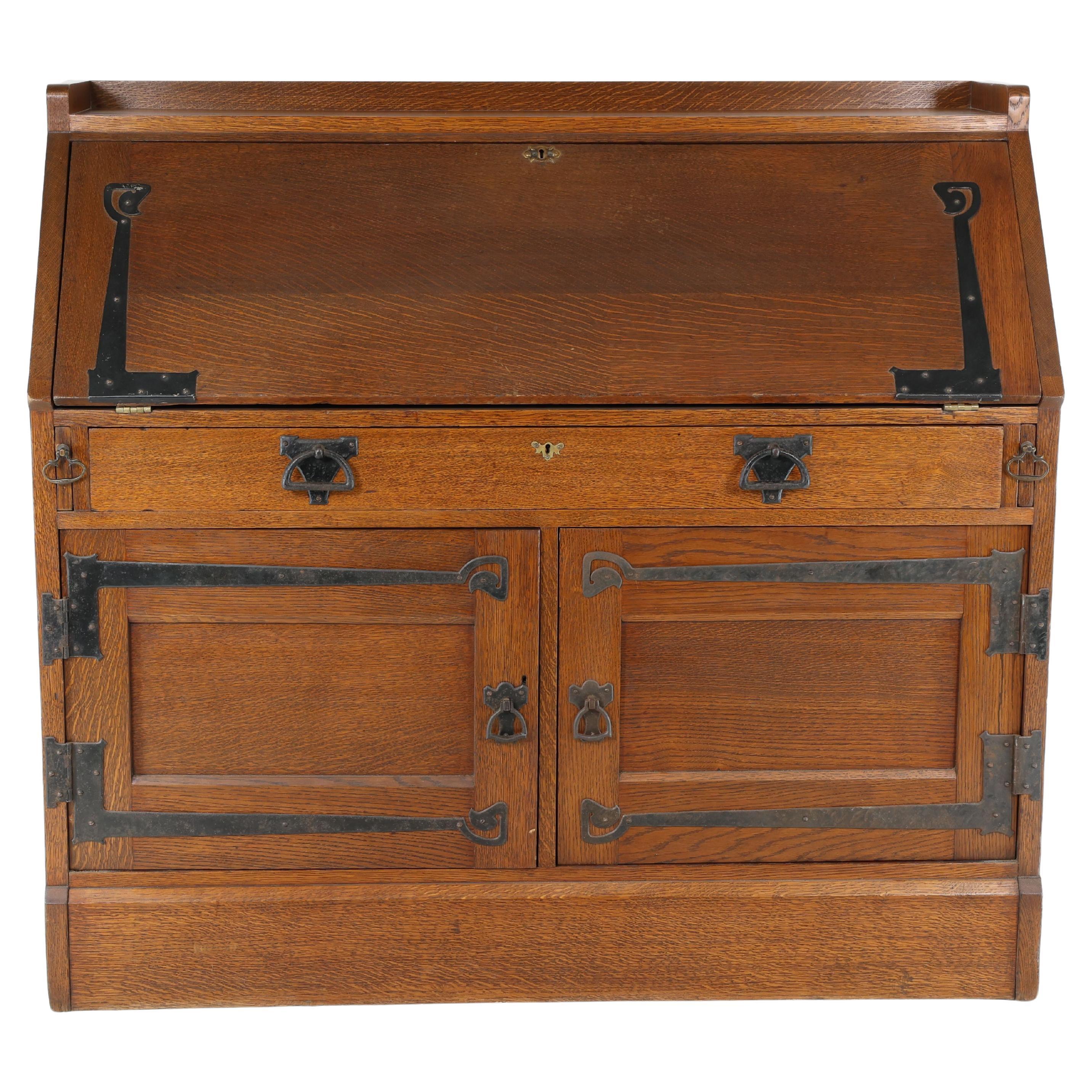 Leonard Wyburd para Liberty & Co. Un buró Arts & Crafts de roble con bisagras de hierro