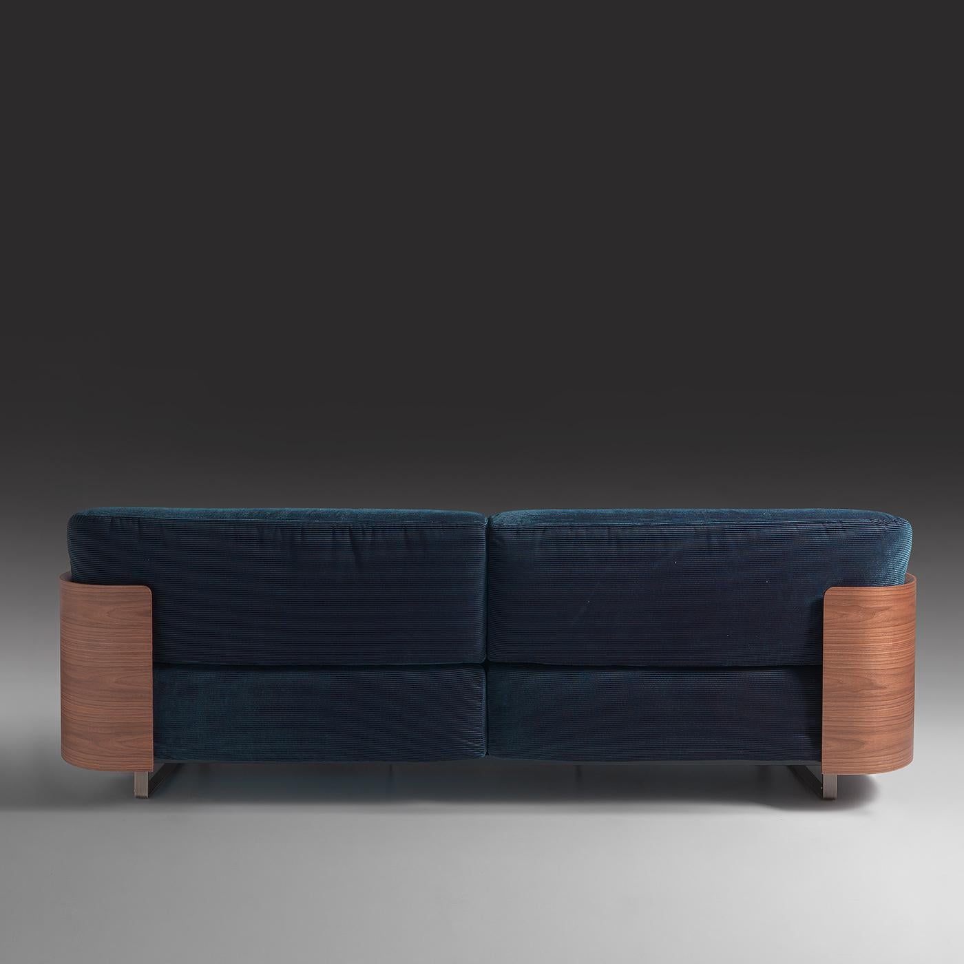 Masterful traditional craftsmanship meets contemporary design in this splendid sofa, handmade of Canaletto walnut wood displaying fully wooden sides. Enriched with two small cylindrical cushions as armrests, it is upholstered with a mesmerizing blue