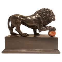 Lion with paw on cannonball