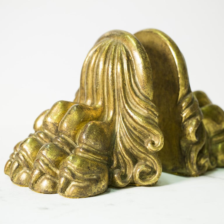 A pair of elegant hand-carved wood book ends by Florentine artisan Castorina. The two pieces in the form of a powerful lion's feet are decorated with gold leaf, worked to reach an antique air.