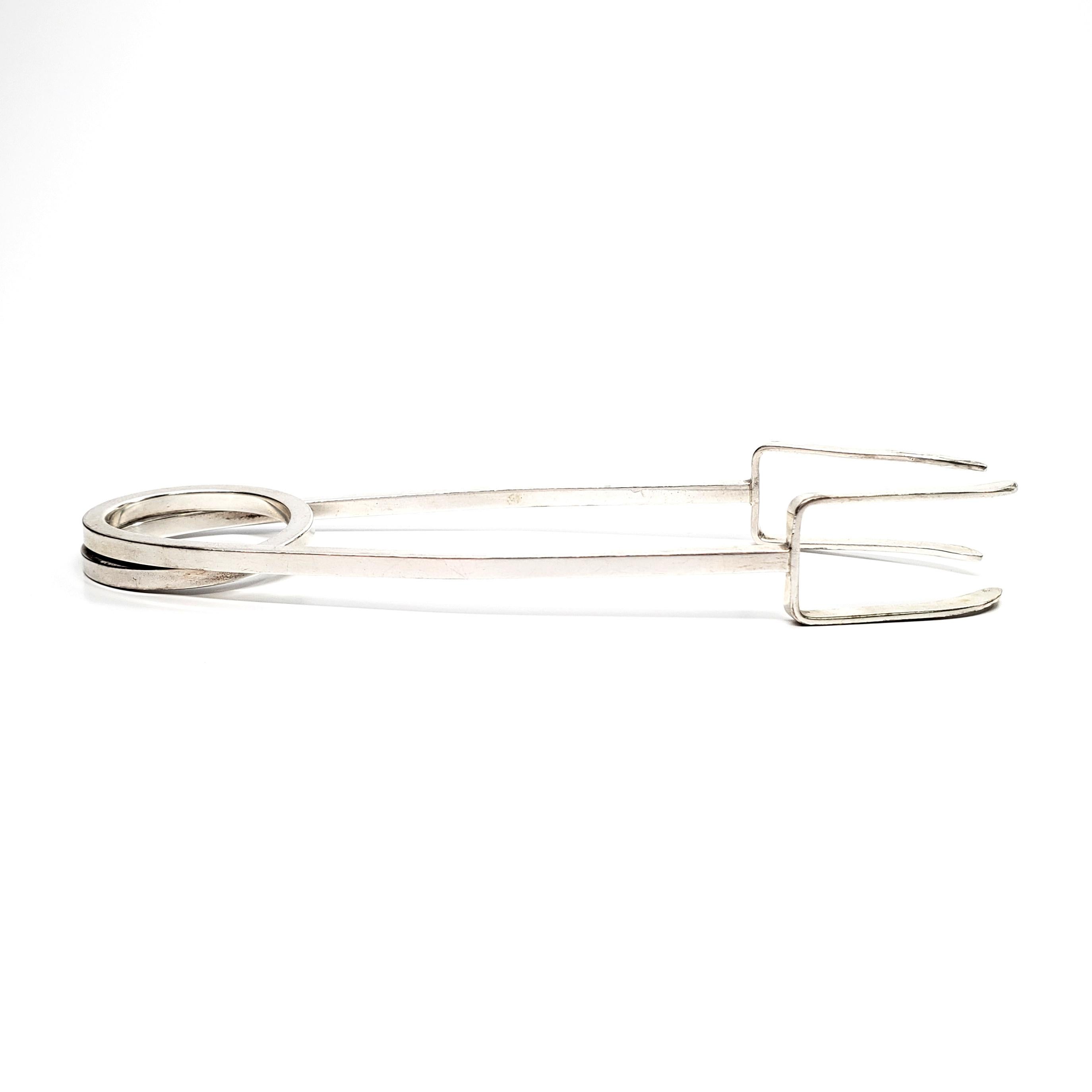 Vintage sterling silver ice tongs designed by Leonore Doskow for Tiffany & Co, circa 1950s.

The modernist design of these tongs feature a continuous rod twisted into a spring. Leonore Doskow designed many silver novelties for upscale