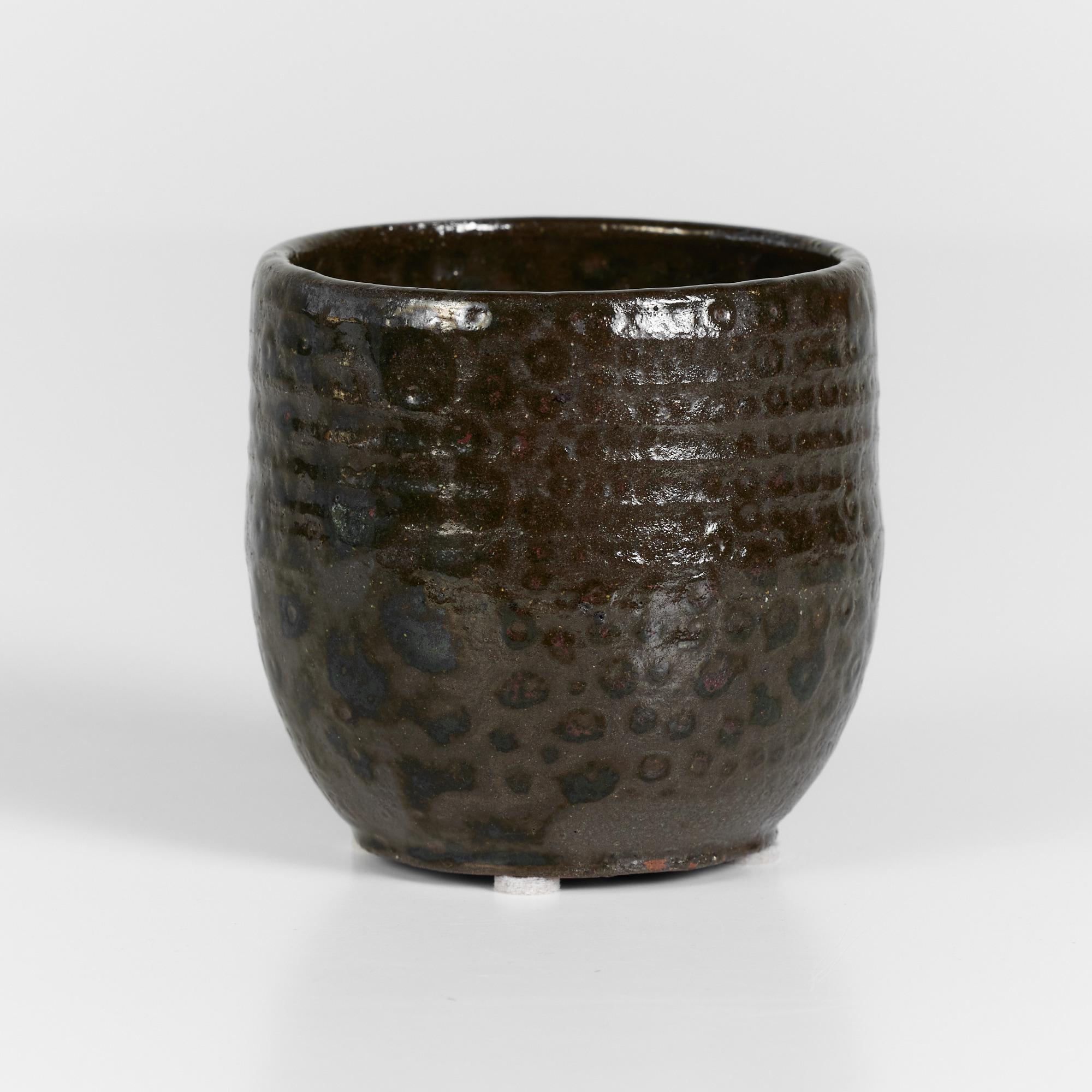 Ceramic piece perfect as a cup or decorative vessel. The exterior features an all over brown matte glaze with high gloss 