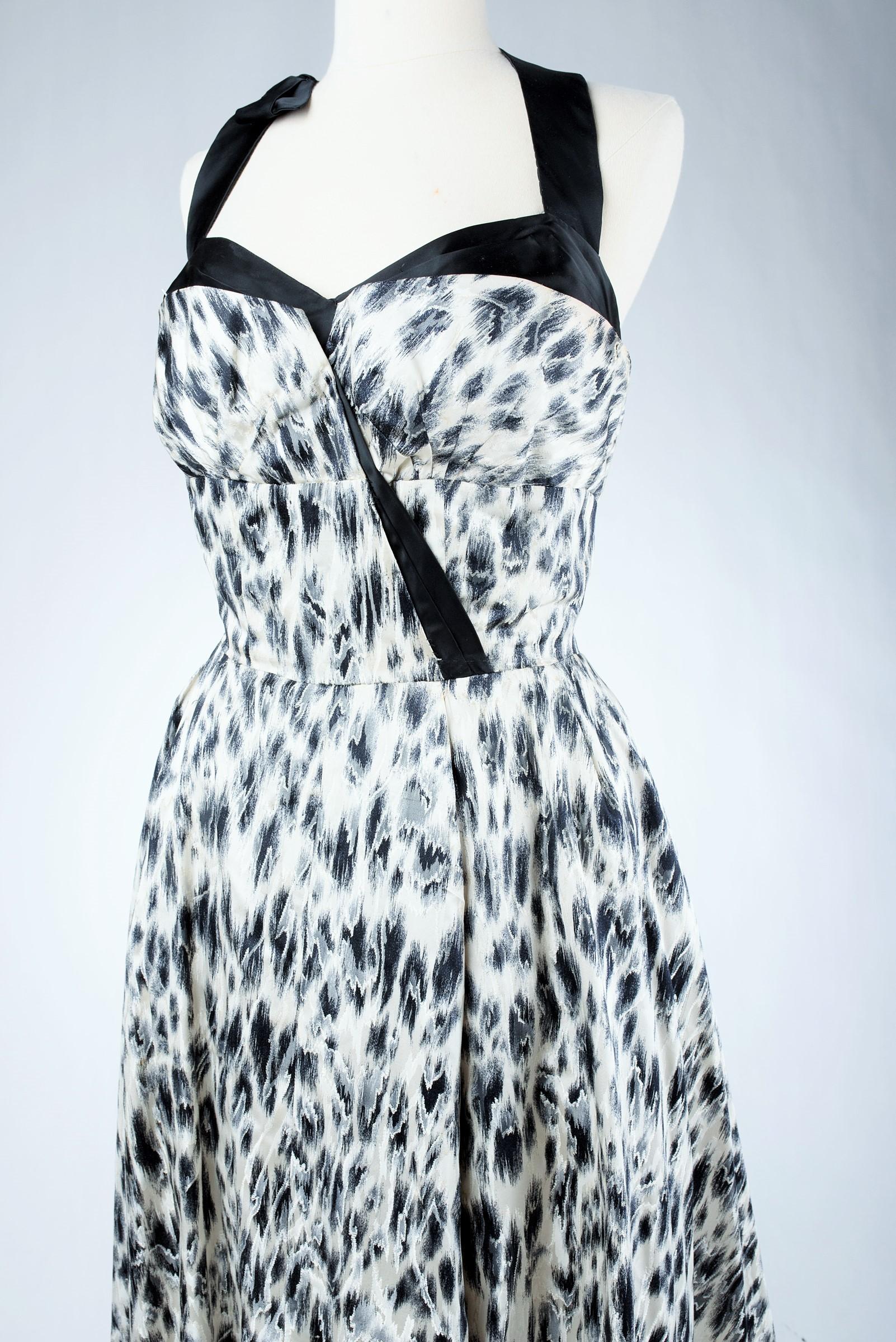 Circa 1955-1960
France
Beautiful Grand soir dress in black and white leopard print satin by Jacques Fath Haute Couture. The whalebone bustier with a large plunging neckline is held by a black satin bow underlining also the balconnet of the chest.
