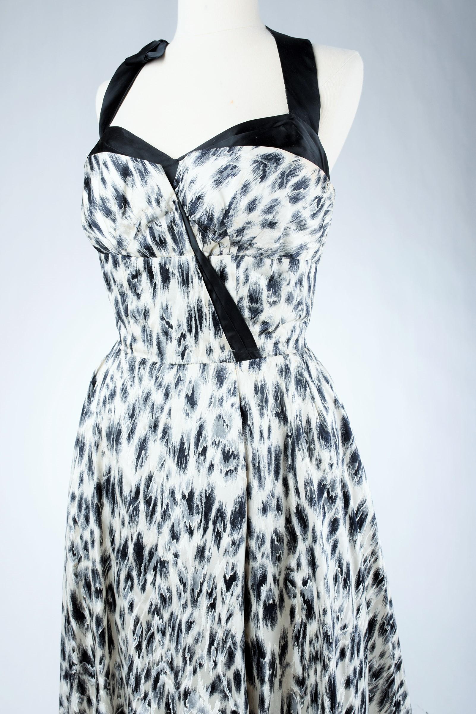 Alrededor de 1955-1960
Francia
Precioso vestido Grand soir de satén con estampado de leopardo blanco y negro de Jacques Fath Haute Couture. El corpiño de ballenas con un gran escote pronunciado está sujeto por un lazo de satén negro que subraya