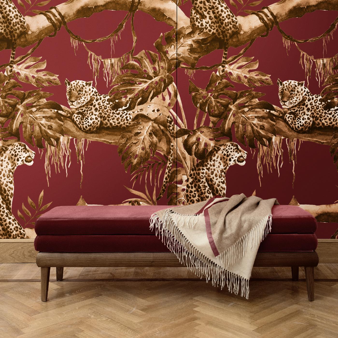 Stunning and unique, the design that adorns this wall covering is part of the Leopards Collection. Over a crimson-hued background, the scene of a leopard sitting under the shade of an exotic tree in golden tones adds a luxurious decoration in any