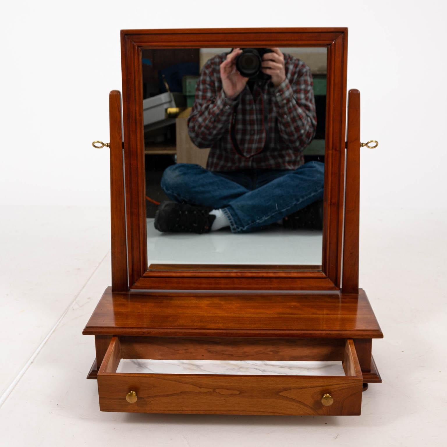 Dresser top shaving mirror in cherrywood with one-drawer that features a brass pull, circa 1958. The piece is signed Leopold Stickley 1958 on mirror back and inside drawer. Please note of wear consistent with age. Made in the United States.