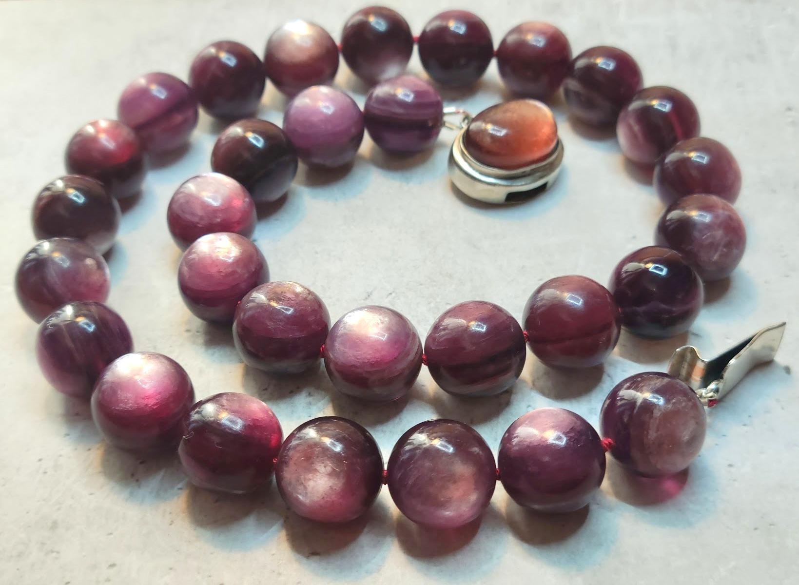 Questa elegante collana misura 49,5 cm di lunghezza e presenta perline rotonde lisce da 15 mm di un ricco colore viola con un bagliore interno. Proveniente dal Mozambico, la lepidolite vanta una tonalità naturalmente vibrante, completamente non