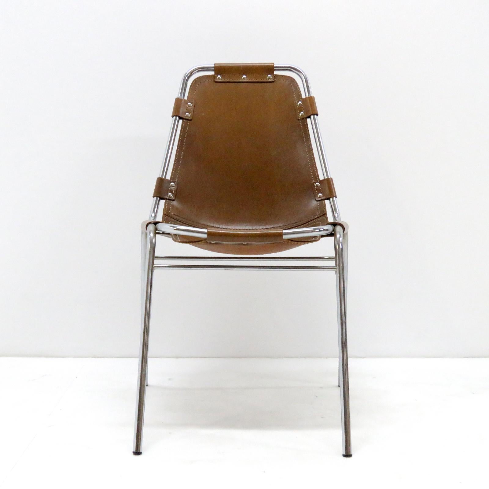 Iconic leather and metal side chairs selected by Charlotte Perriand for the Ski resort Les Arcs in 1960, with chrome tubular frame in great condition and high quality thick leather seat with a fantastic patina to the leather. Two chairs available,