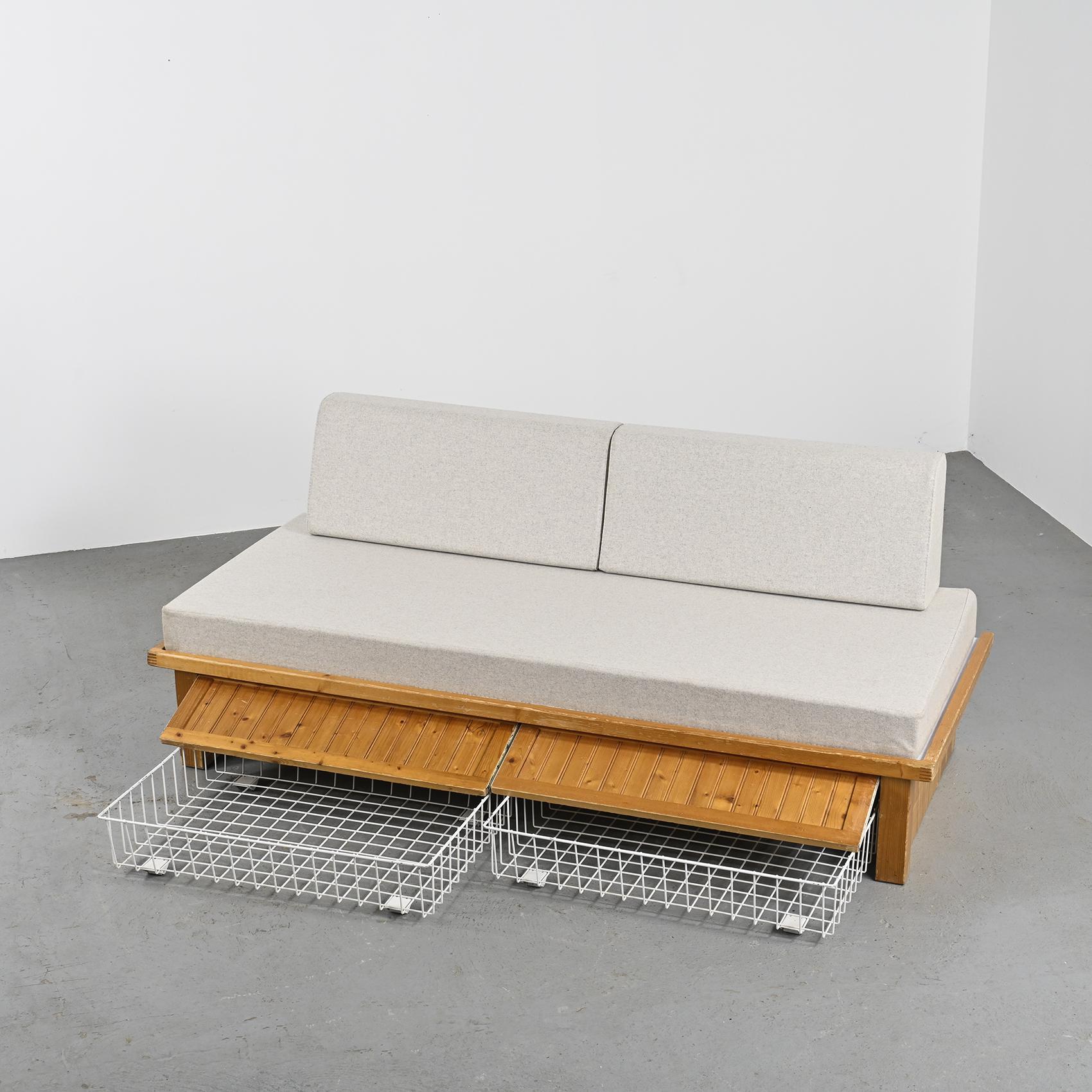 A bench or bed that equipped the flats of the Nova residence in Les Arcs, furbished by Charlotte Perriand.
 
The pine slatted base structure contains two rolling drawers accessible through a flap. The bench seat has a mattress and foam cushions