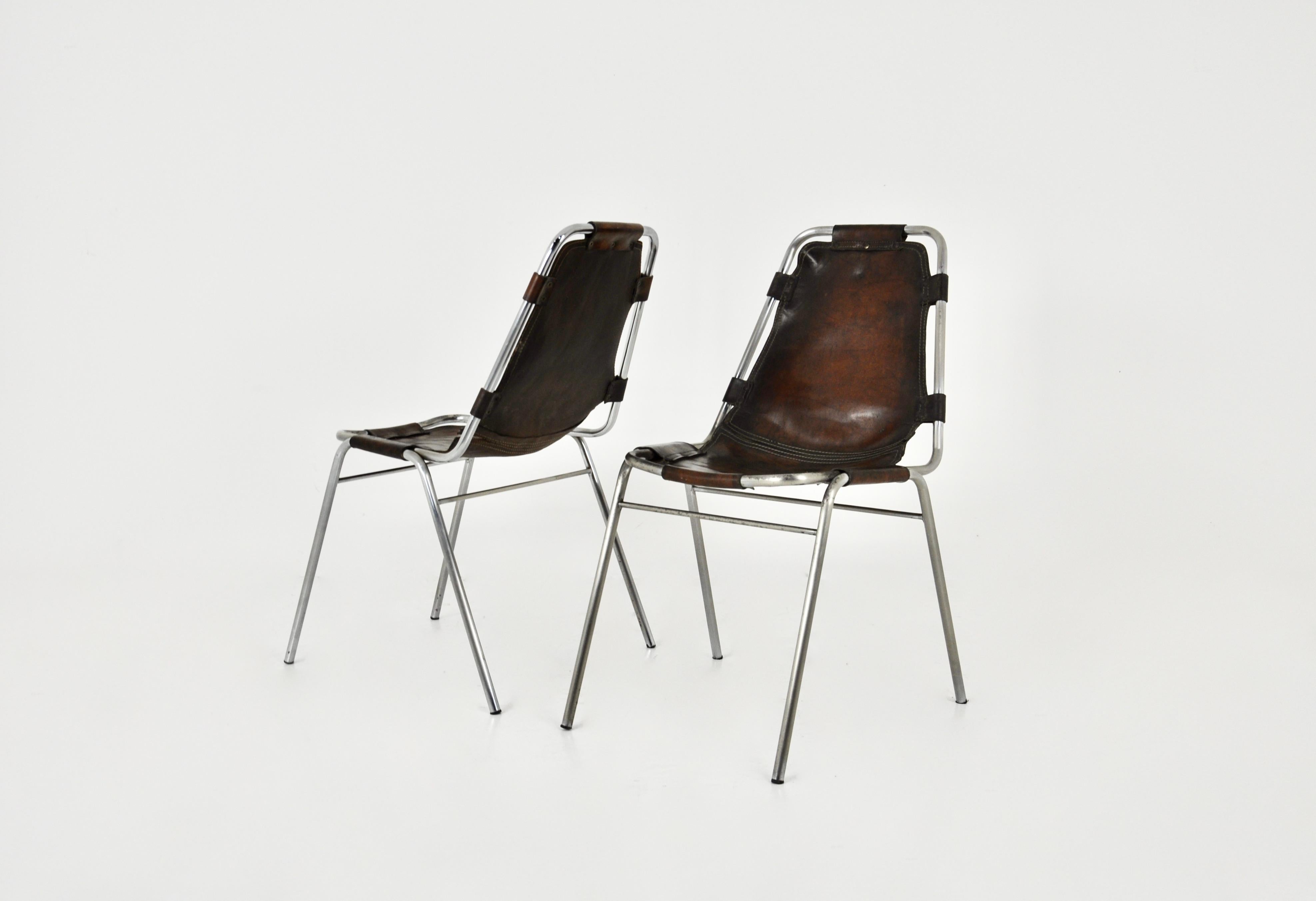 Ensemble de 2 chaises en cuir et métal chromé. Ce modèle a été conçu par Charlotte Perriand pour la station de ski française des Arcs dans les années 1960. Hauteur du siège : 43 cm. Usure due au temps et à l'âge des chaises.