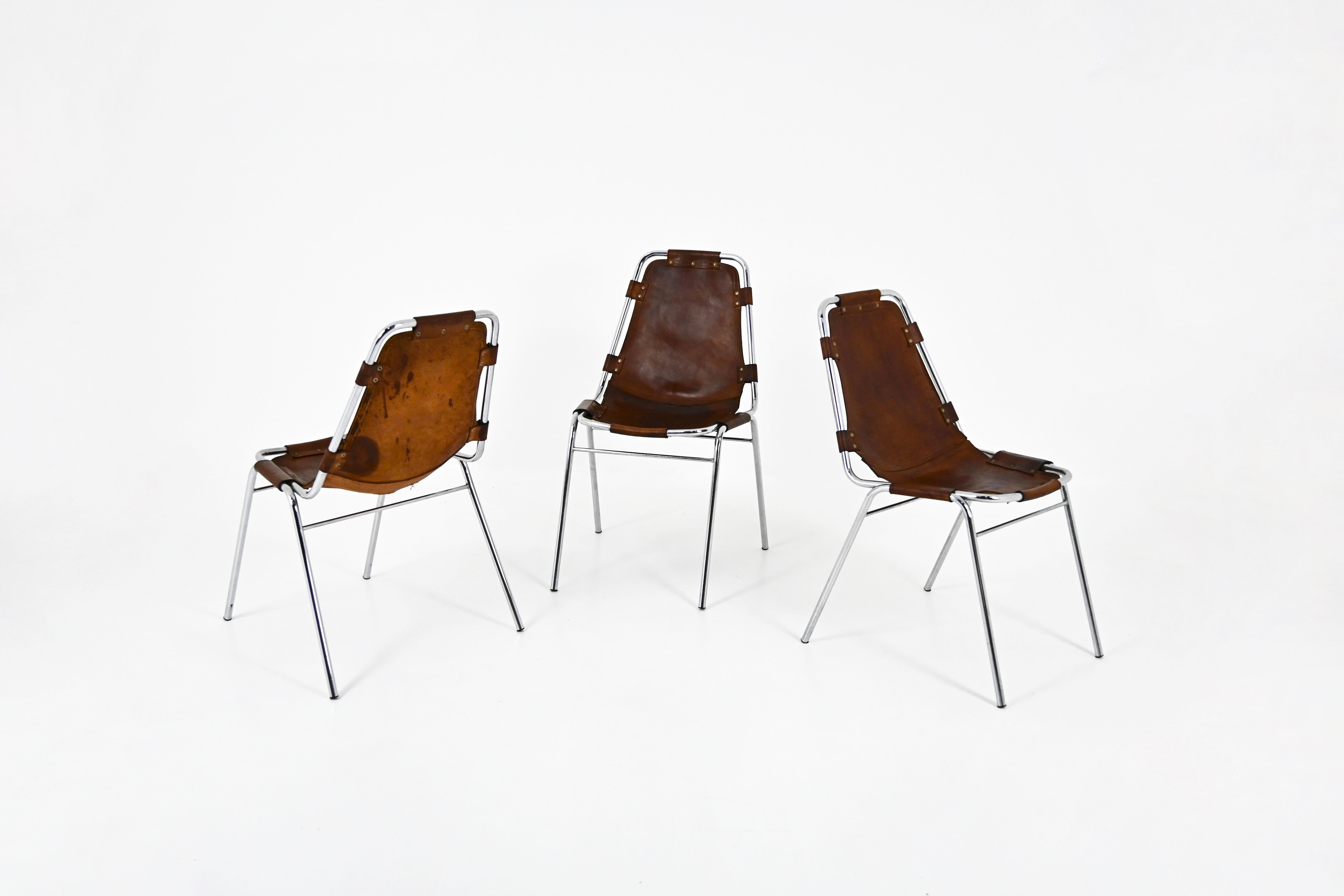 Set of 3 chairs in leather and chromed metal. This model was designed by Charlotte Perriand for the French ski resort of Les Arcs in the 1960s. Seat height: 45 cm. Wear due to time and age of the chairs.