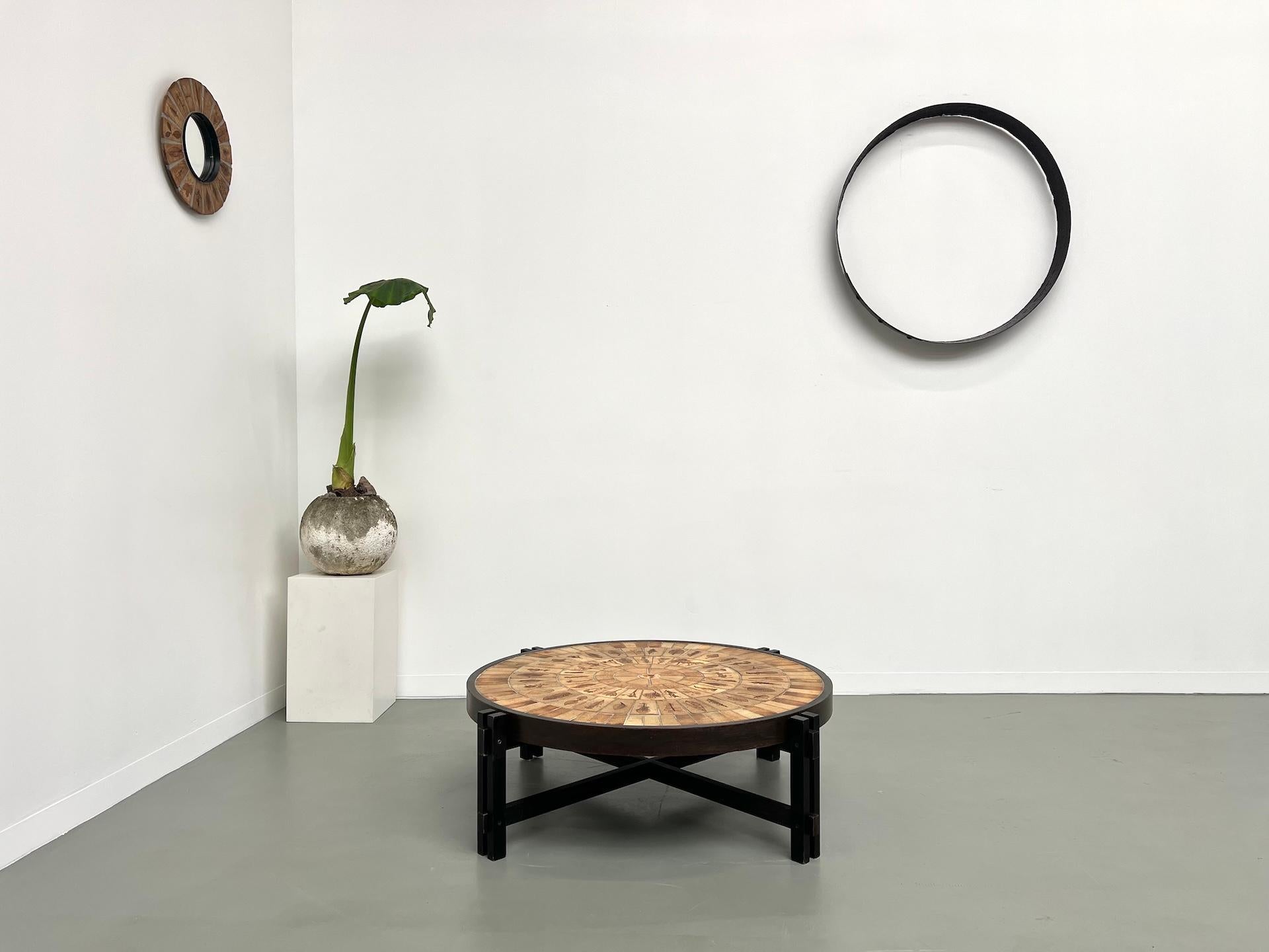 Cette table basse emblématique a été créée par le céramiste français Roger Capron dans les années 1960. Il se compose d'un cadre en bois massif et en contreplaqué et d'un plateau en carreaux de céramique avec un motif d'herbier. Chaque tuile est