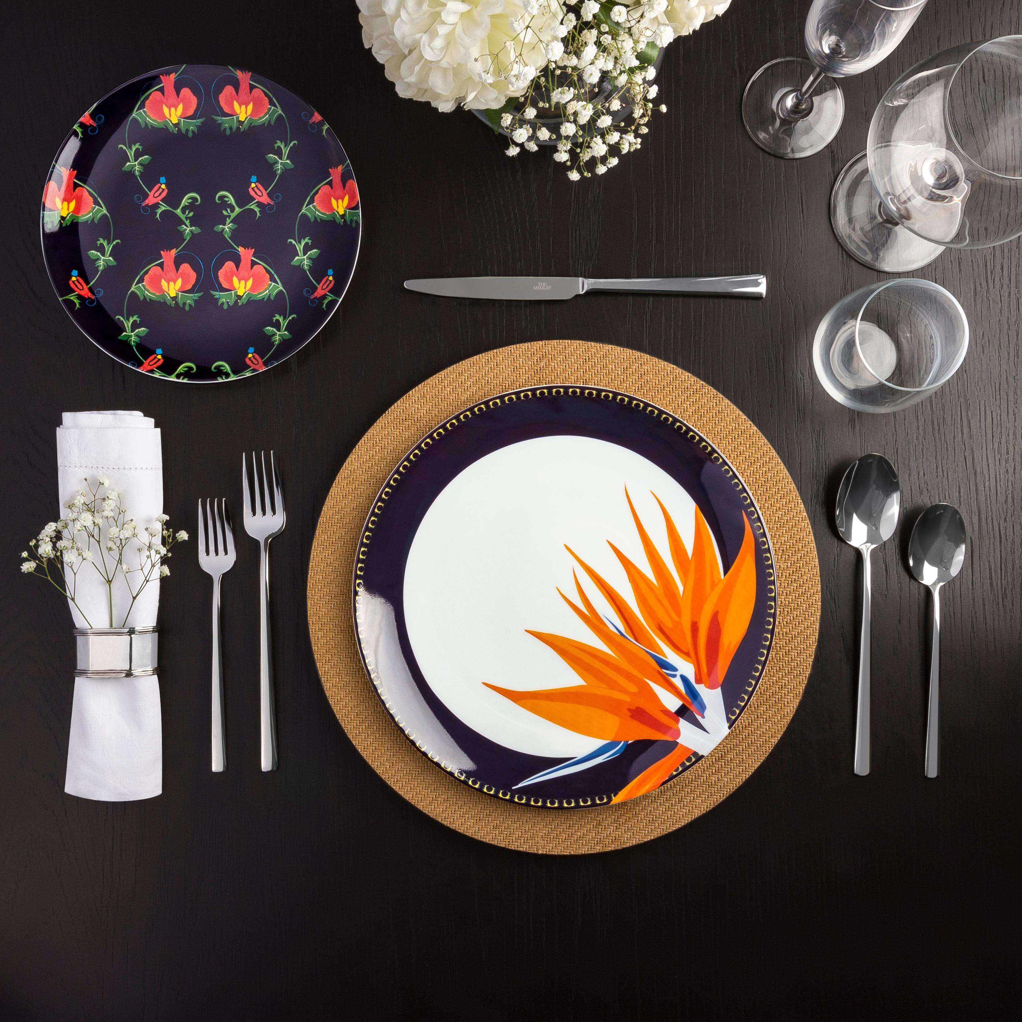 The Les Paradis Dessert Plate showcases the elegant dance of the bird of paradise in delightful M.HASAN signature pattern. Accents of green, orange and red rest on a plain on aubergine, this plate will be a colorful addition to your dining