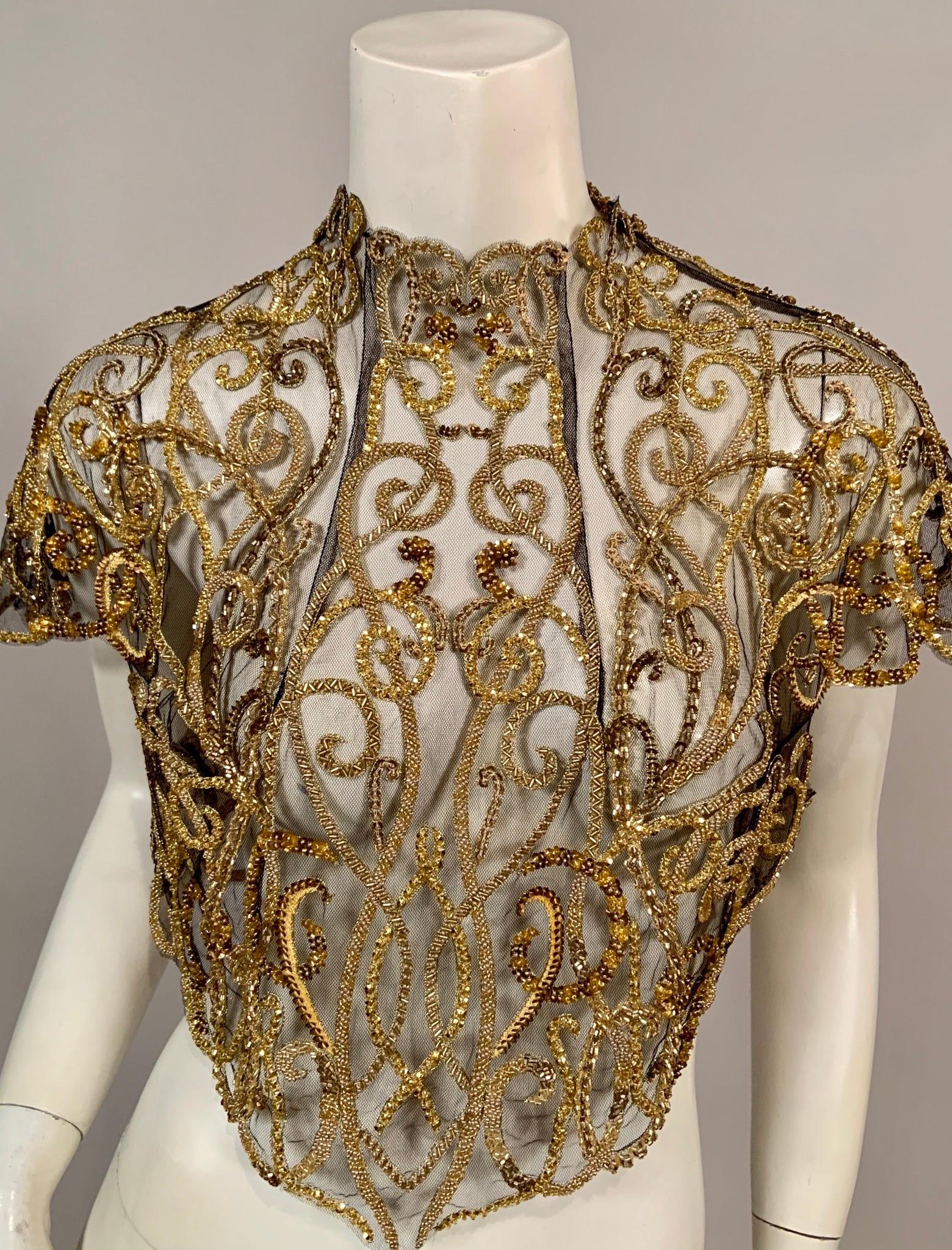 Every type of gold bead or sequin imaginable is used to great advantage on this sheer black tulle bodice or blouse. The design is reminiscent of the beautiful scrolling iron work that one would see in Paris. It is edged with the most delicate gold