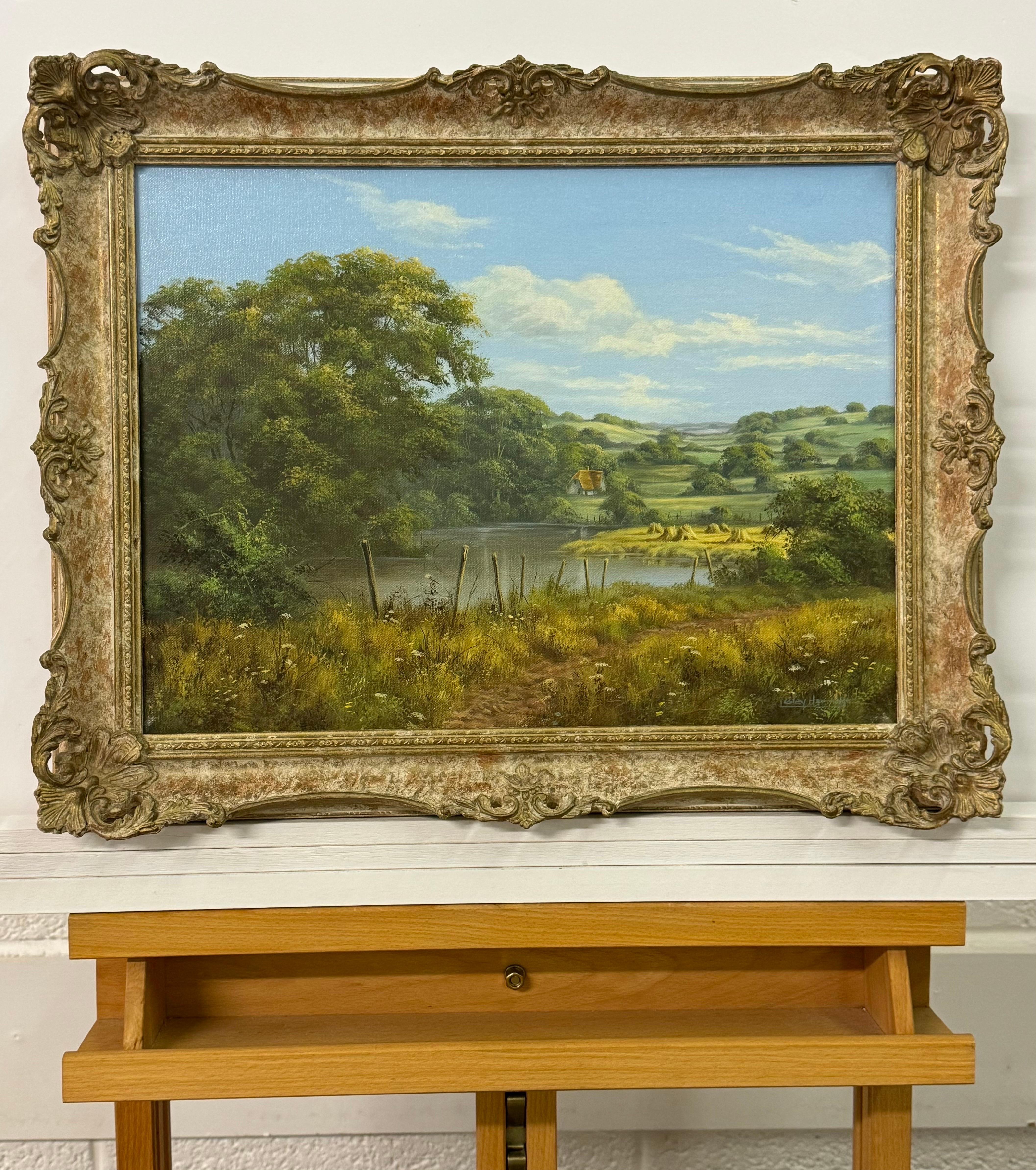 Lush Green English Countryside with Cottage & River by British Landscape Artist, Lesley Hammett (Born 1955)

Art measures 16 x 12 inches 
Frame measures 19 x 15 inches 

This painting captures the idyllic charm of a pastoral countryside with