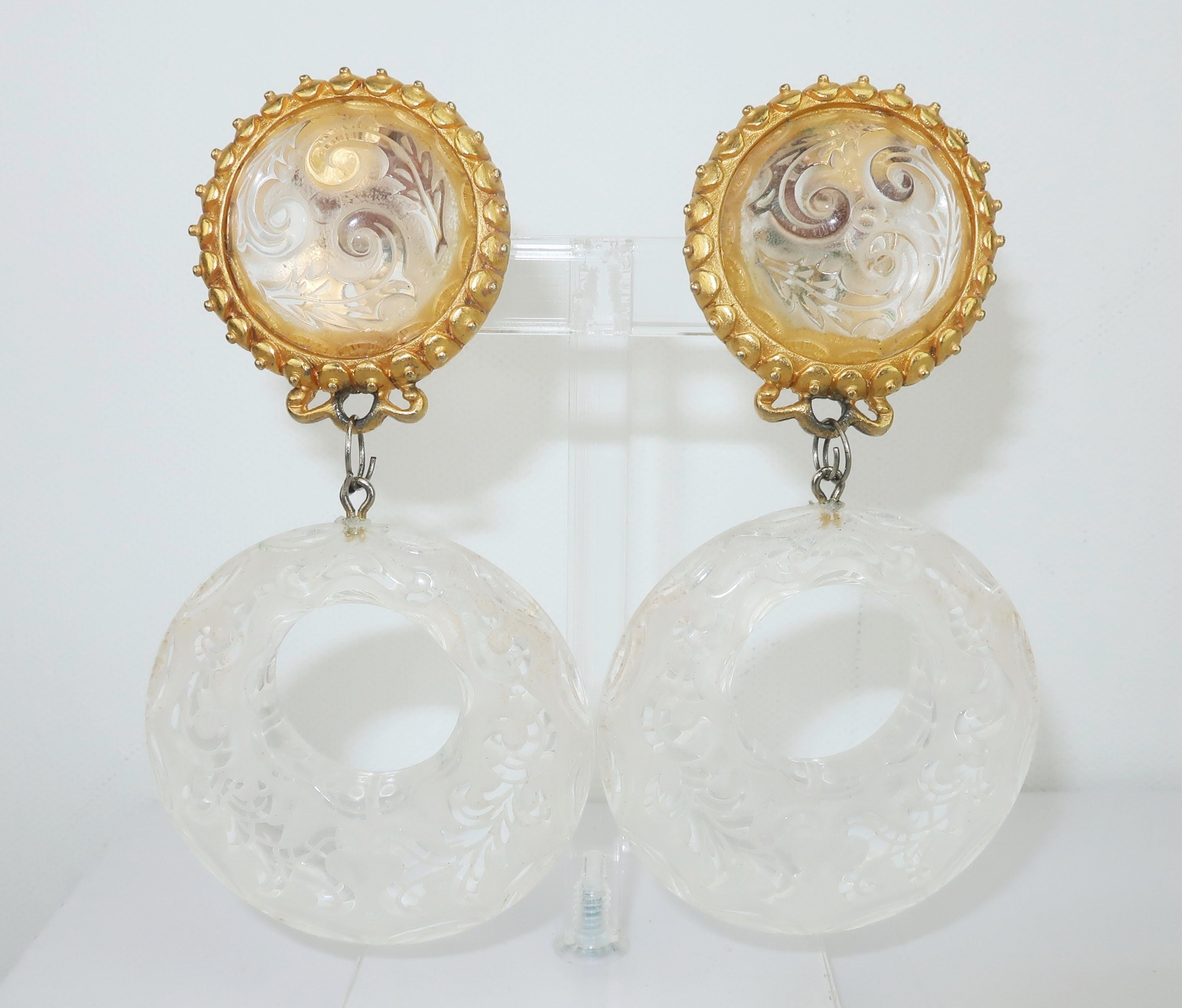 Leslie Block blends baroque opulence and 1980's glam with these carved lucite hoop dangle earrings.  The gold tone setting offers comfortable clip on hardware.  Signed at the back of one earring.
CONDITION
Overall good to fair condition with some