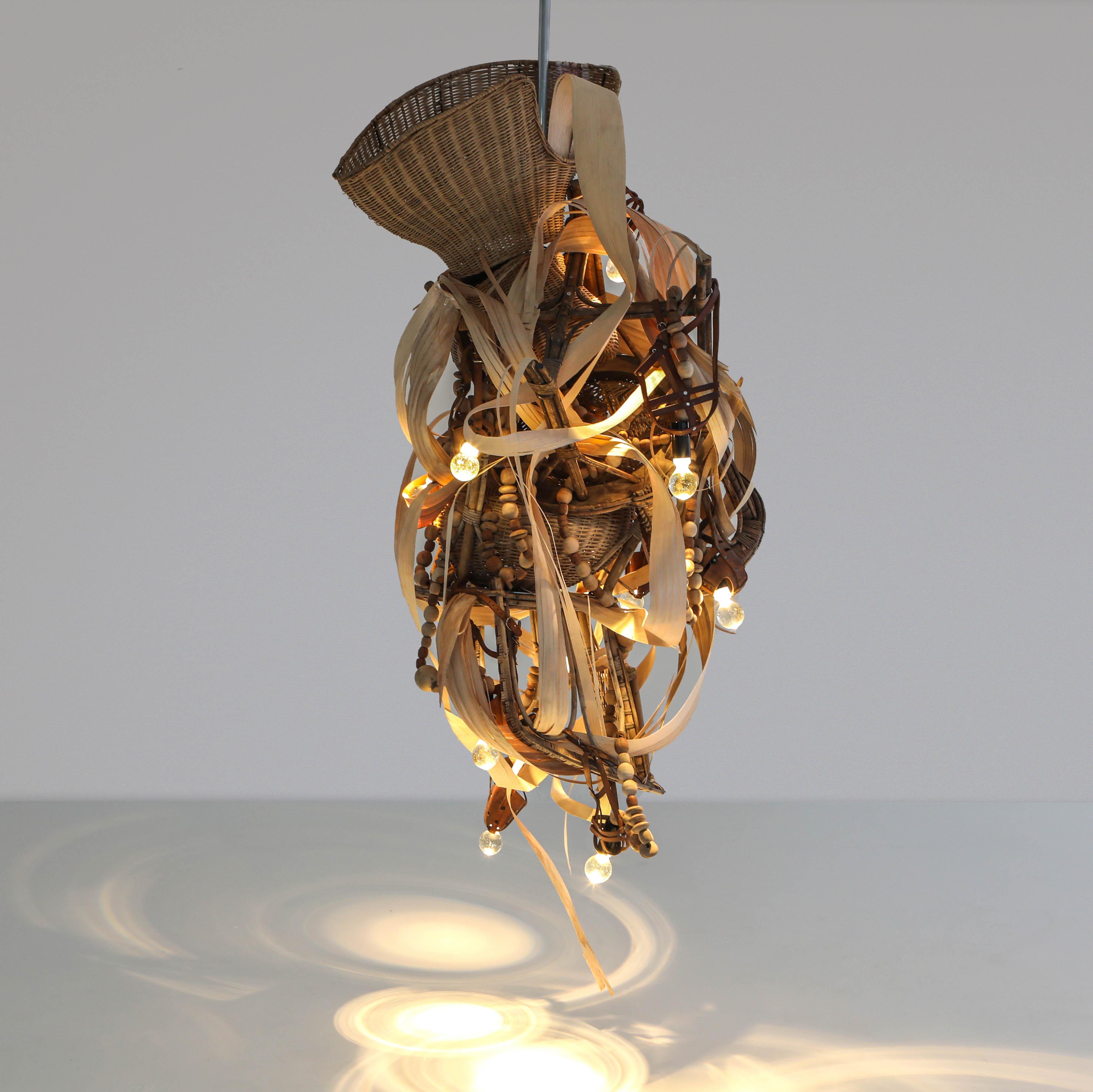 The ‘Let Me Talk’ chandelier is a functional art and collectable design piece constructed from assembled rattan seats, slips of veneer in tulip tree and oak wood. The light fixtures made with handcrafted carafe glass cabochons. The structure is