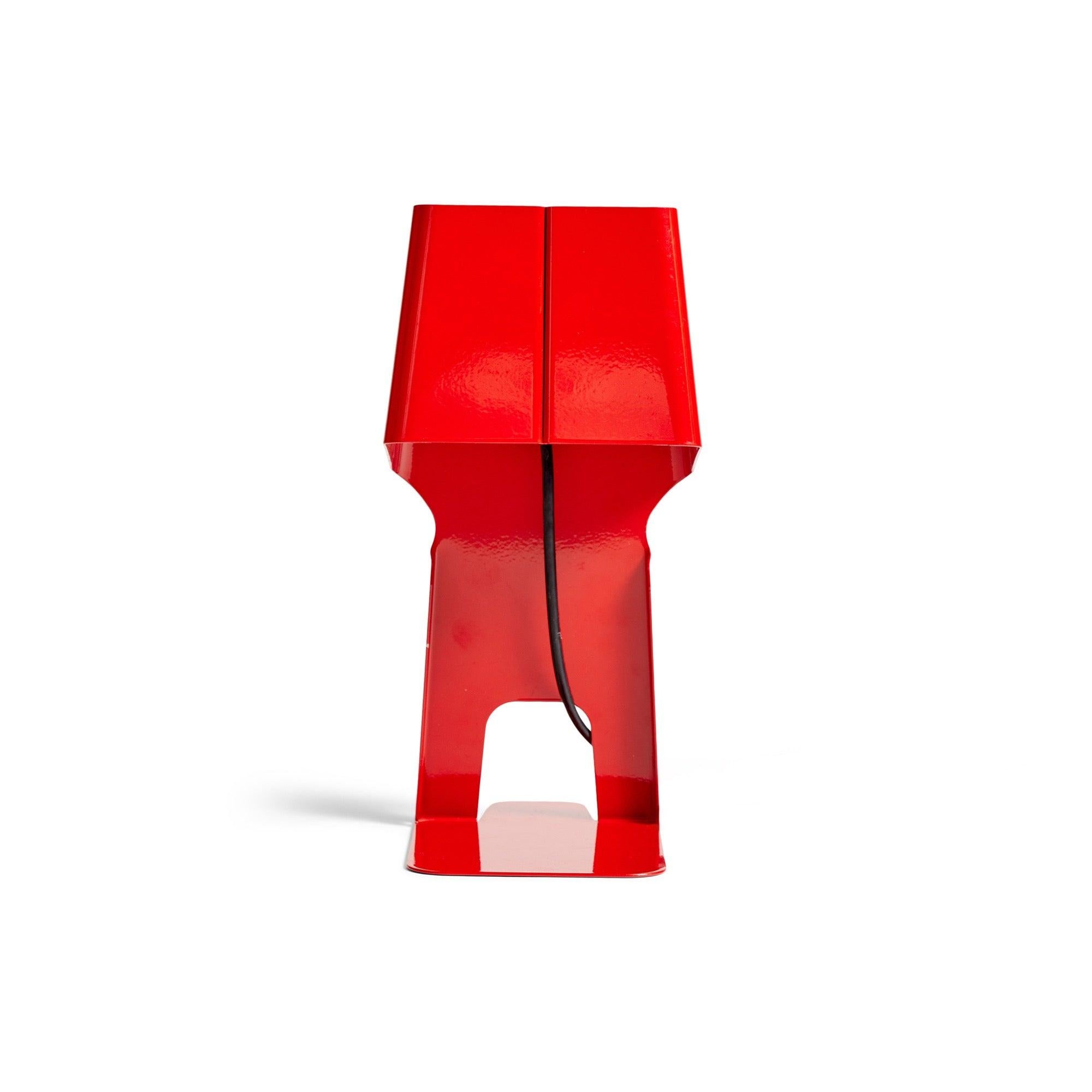 A functional table lamp to be used as a bookend or document stand, formed using a single piece of bent lacquered metal.
