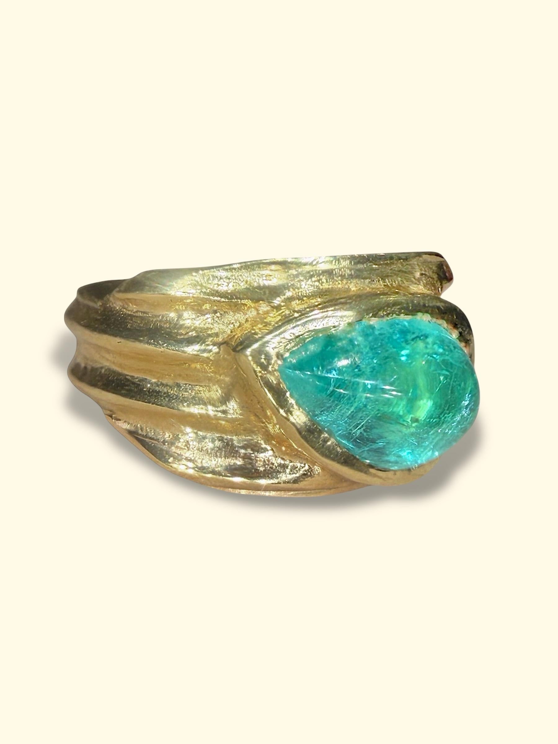 Una oda a las formas antiguas reimaginadas para hoy.

Este escultural anillo de puros de oro amarillo de 18 quilates presenta un cabujón de turmalina Paraíba de Mozambique en forma de pera de 2,5 quilates, que brilla con luminosidad oceánica.