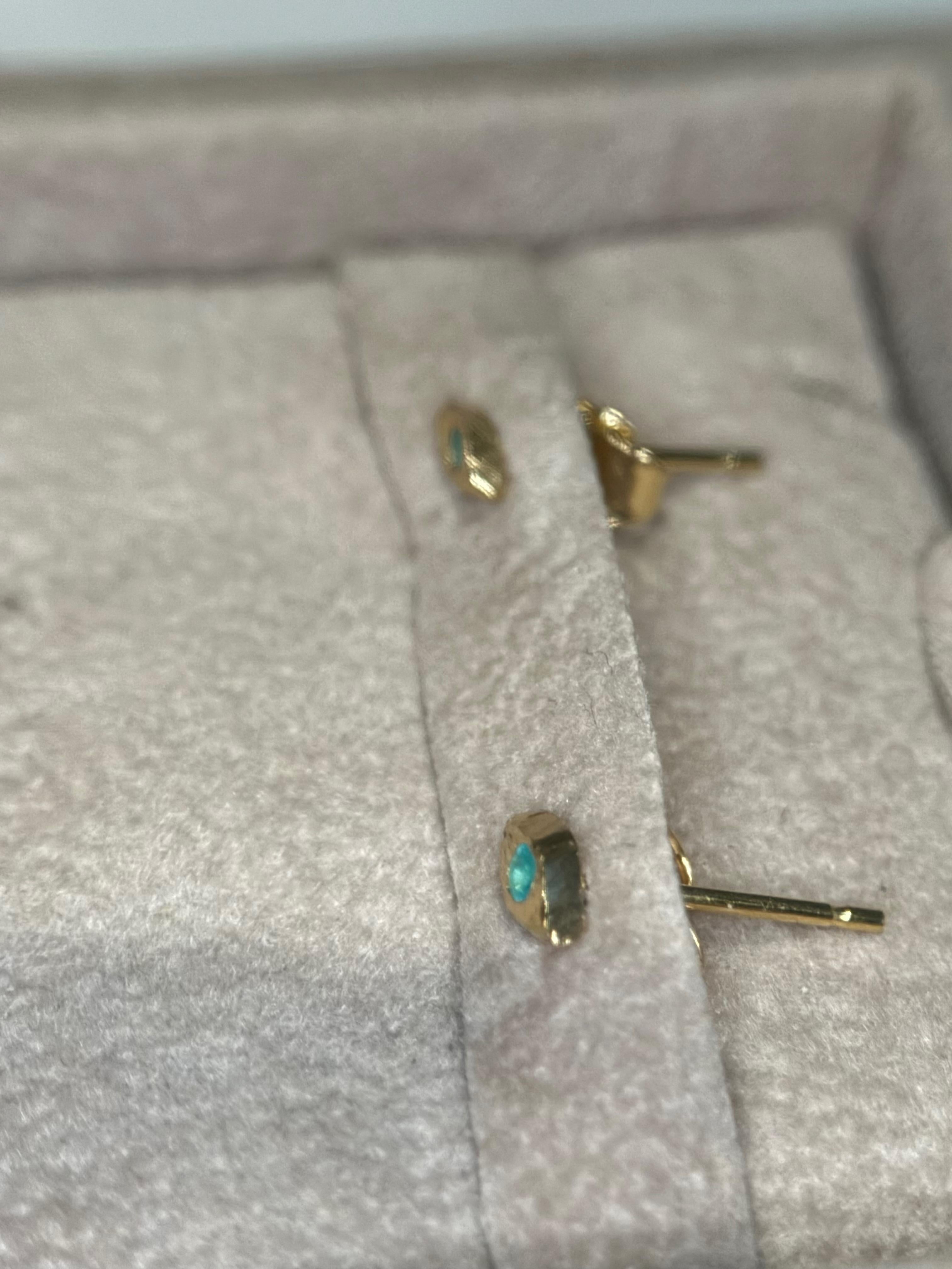 Il malocchio, un simbolo secolare di protezione, è rappresentato con eleganza in queste mini borchie. La sorprendente combinazione di pietre paraiba blu neon, note per la loro rarità, incastonate nel metallo dorato crea un contrasto accattivante che