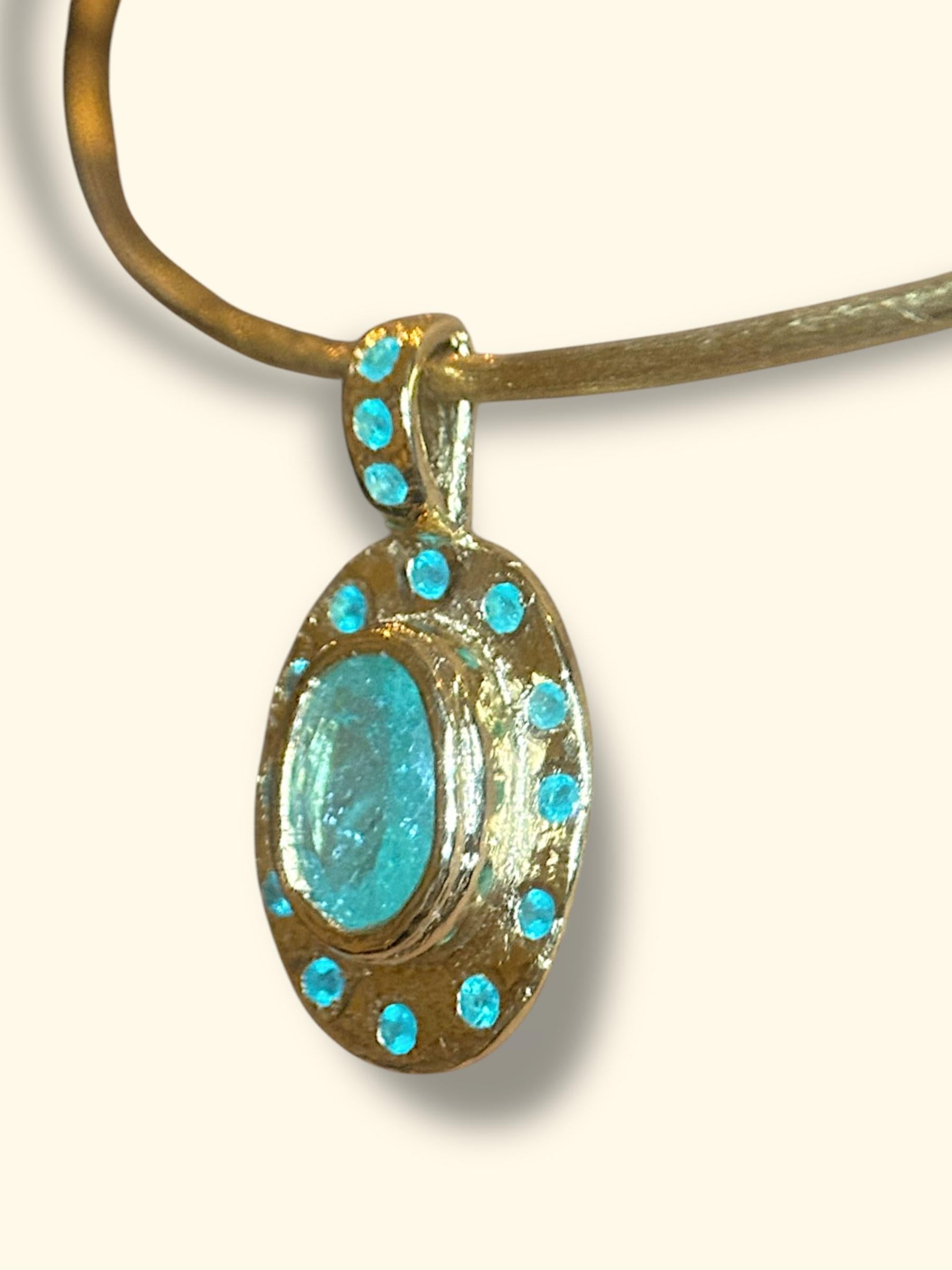 Questa è una collana di tormalina Paraiba unica nel suo genere, realizzata a mano in oro giallo 18 carati, che combina una grande Paraiba ovale verde blu certificata di 2 carati proveniente dal Mozambico e decorata con rari tondi di Paraiba blu neon