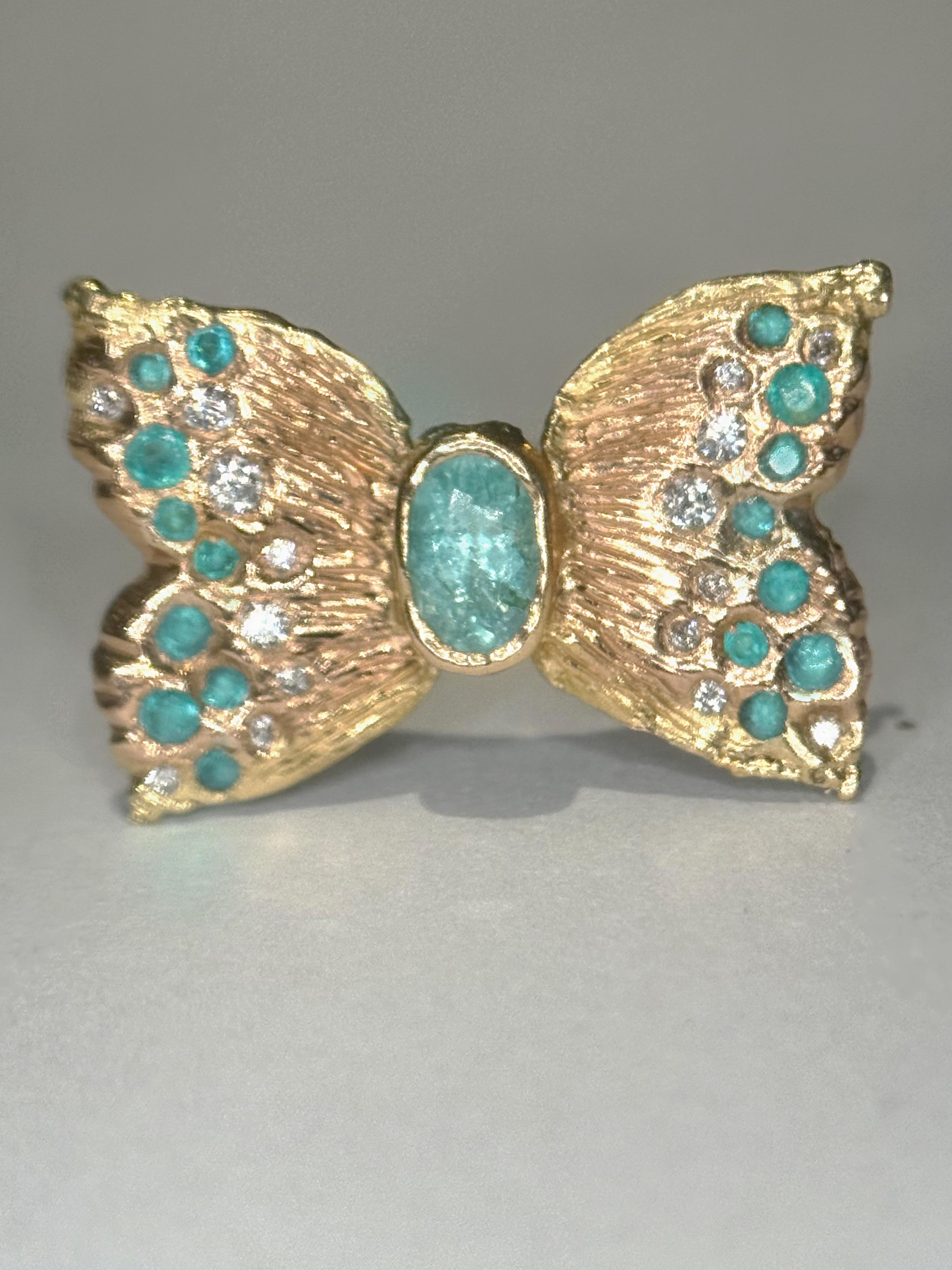 Un anello da cocktail di grande effetto, che mostra un'affascinante farfalla con una luminosa tormalina Paraibas del Mozambico.  e impreziosito da tormaline Paraibas blu neon dei Caraibi e diamanti bianchi che conferiscono all'anello un aspetto