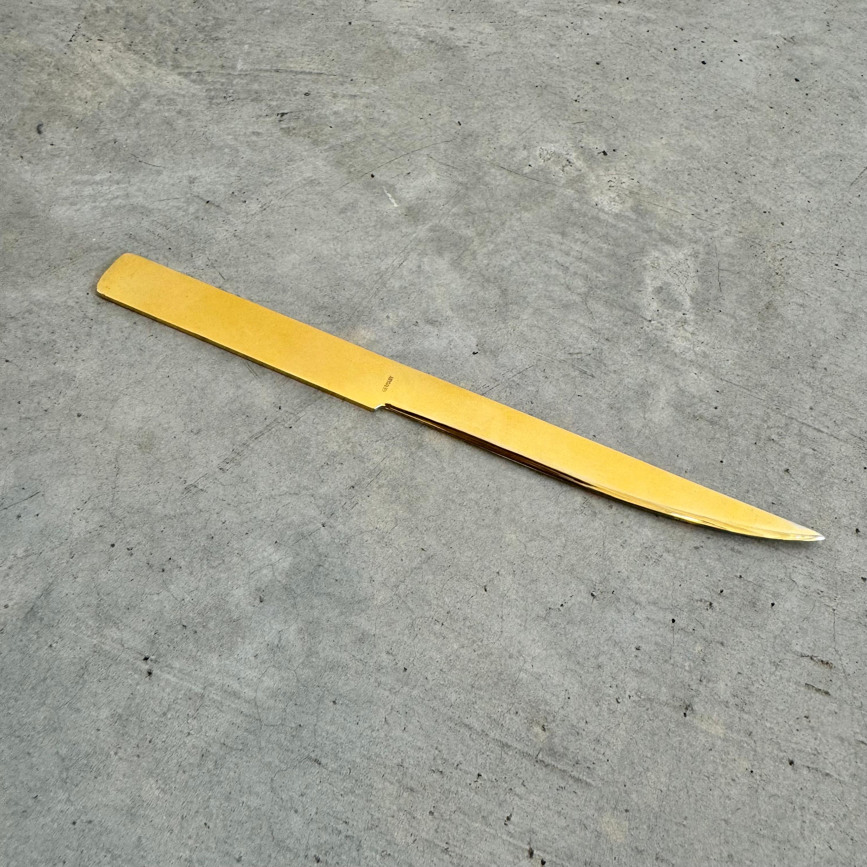 Elegant gold colored metal letter opener with a metric ruler engraved along top edge. 'Germany' stamped on the underside right above the hilt of the handle. Light patina to the gold finish. This piece is a minimal and practical addition to elevate