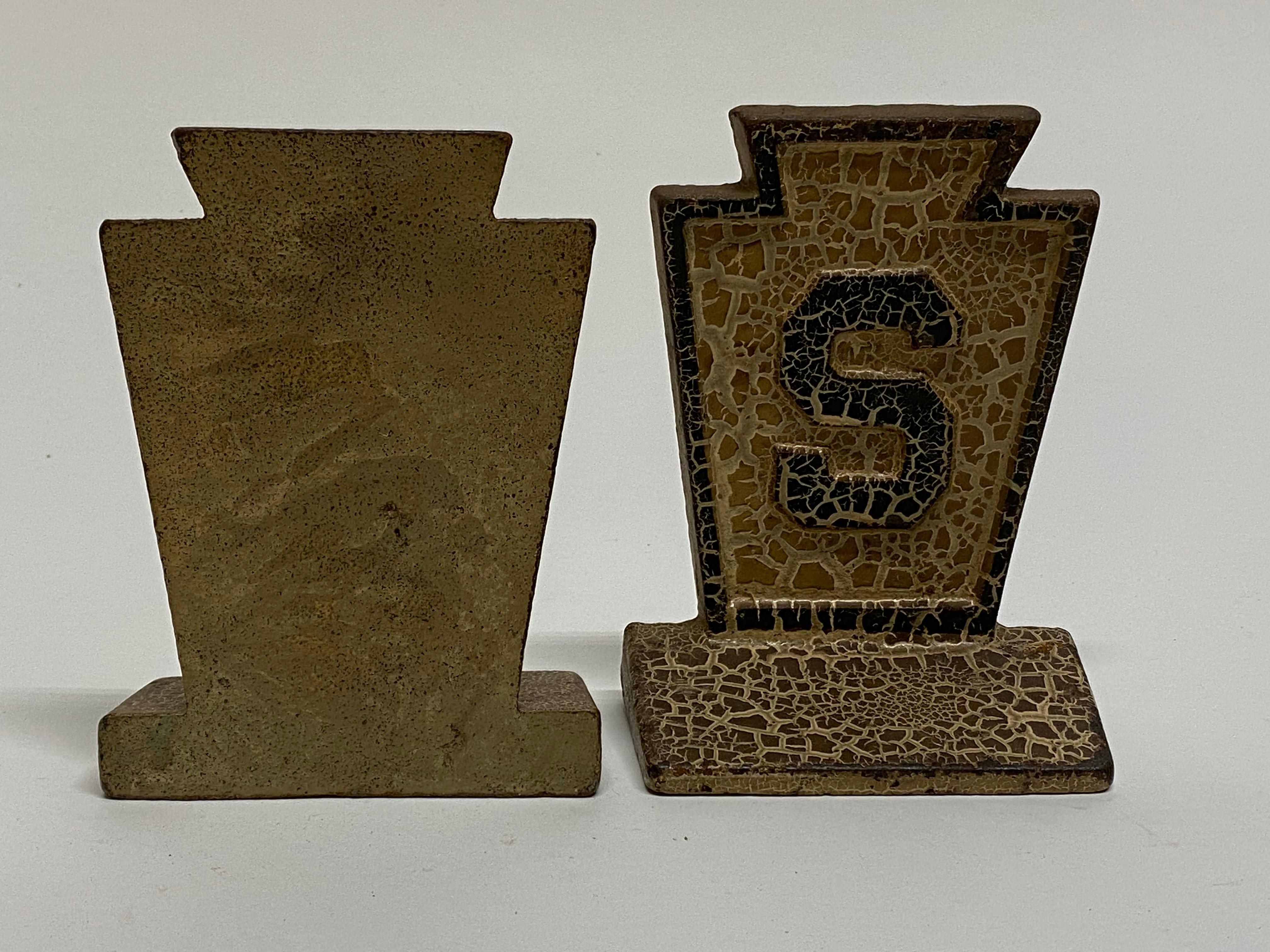 A nice pair of cast iron bookends with great patina, surface, and texture. The bookends are a keystone shape with a raised letter 'S', circa 1920-30. A good looking set that would compliment any library, desk, office or anywhere in the home. Good